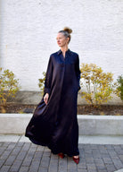 Image featuring a woman modeling the TWP Jennys oversized maxi shirt dress in sleek navy blue silk charmeuse.