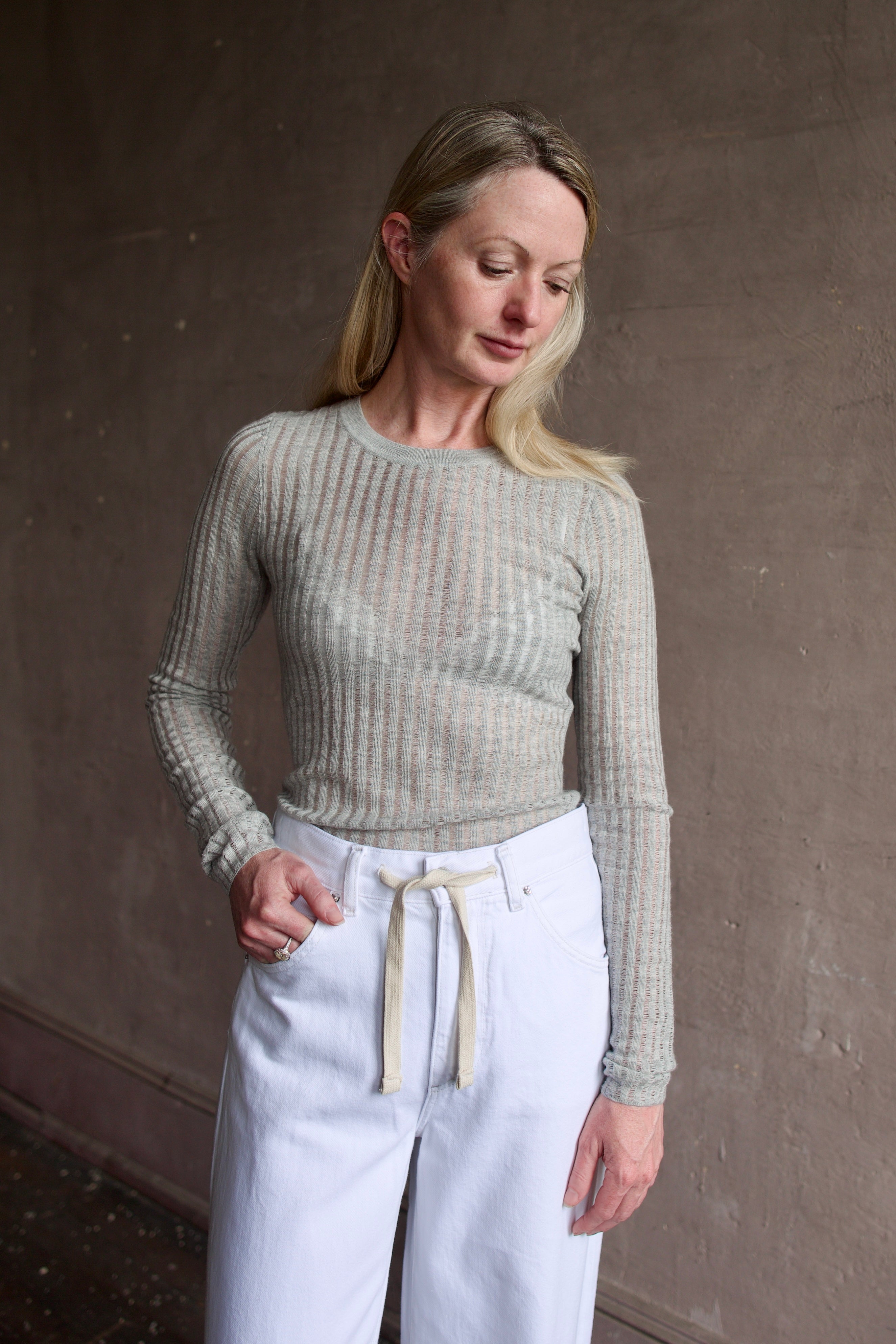 Mature woman wearing luxury brand TWP grey fine cashmere pointelle knit crewneck top perfect lightweight layering in cool weather 