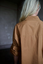 Close up detail of model wearing a TWP shirt embellished with crystals in a warm brown 