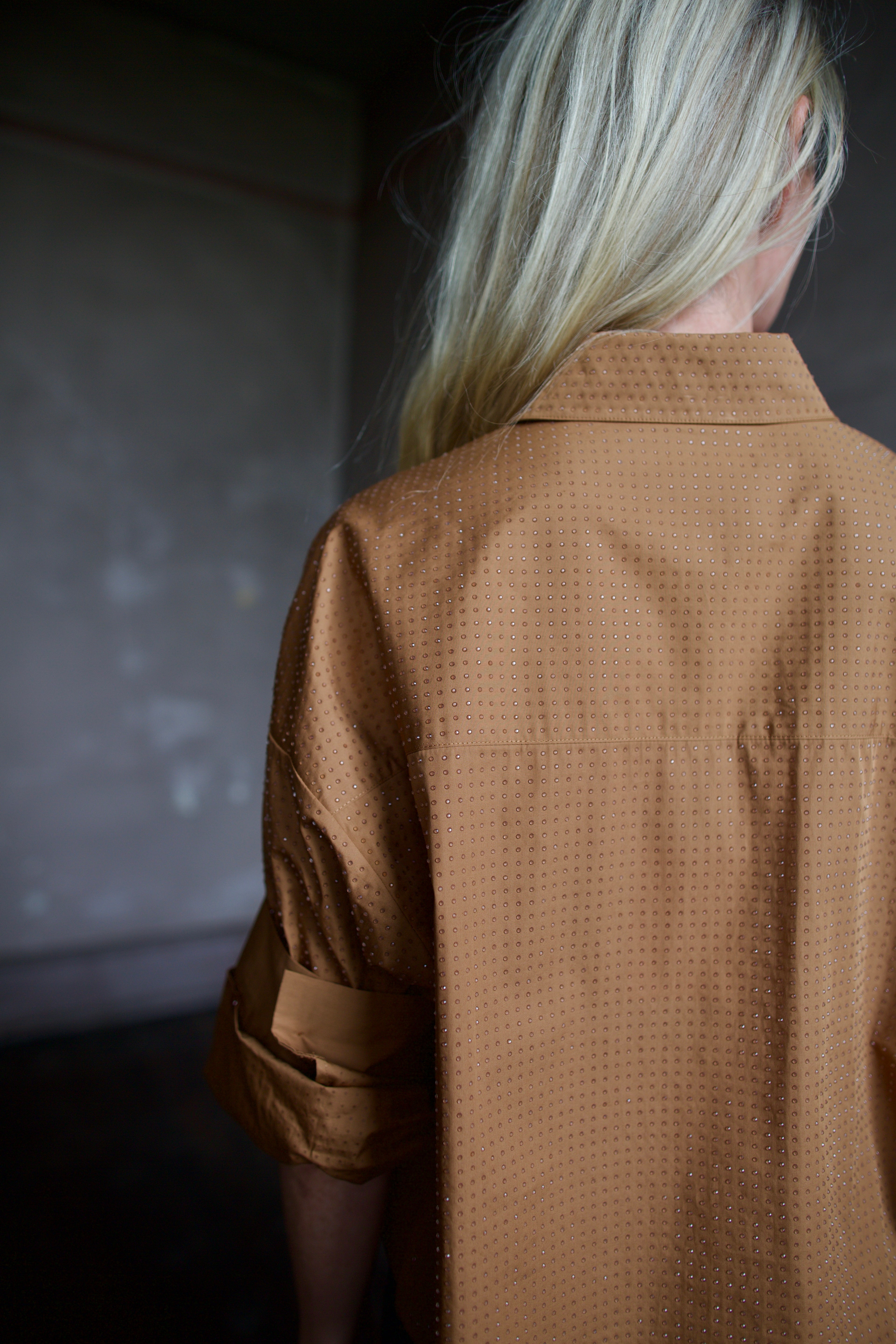 Close up detail of model wearing a TWP shirt embellished with crystals in a warm brown 