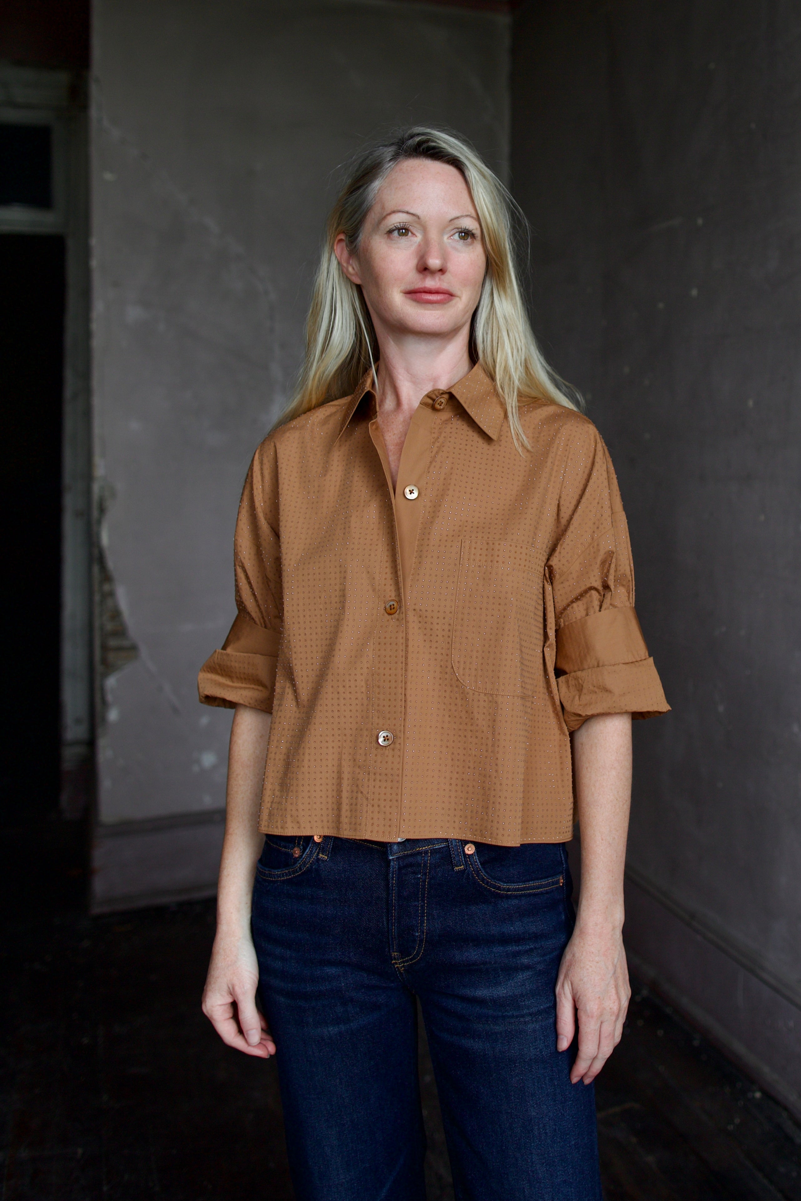Mature model wearing the epitome of casual chic in a brown TWP shirt embellished with crystals and dark denim