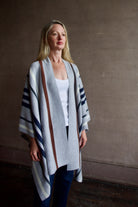 Mature Model wearing gray TWP luxury Italian cashmere poncho with brown and navy stripes and dark denim
