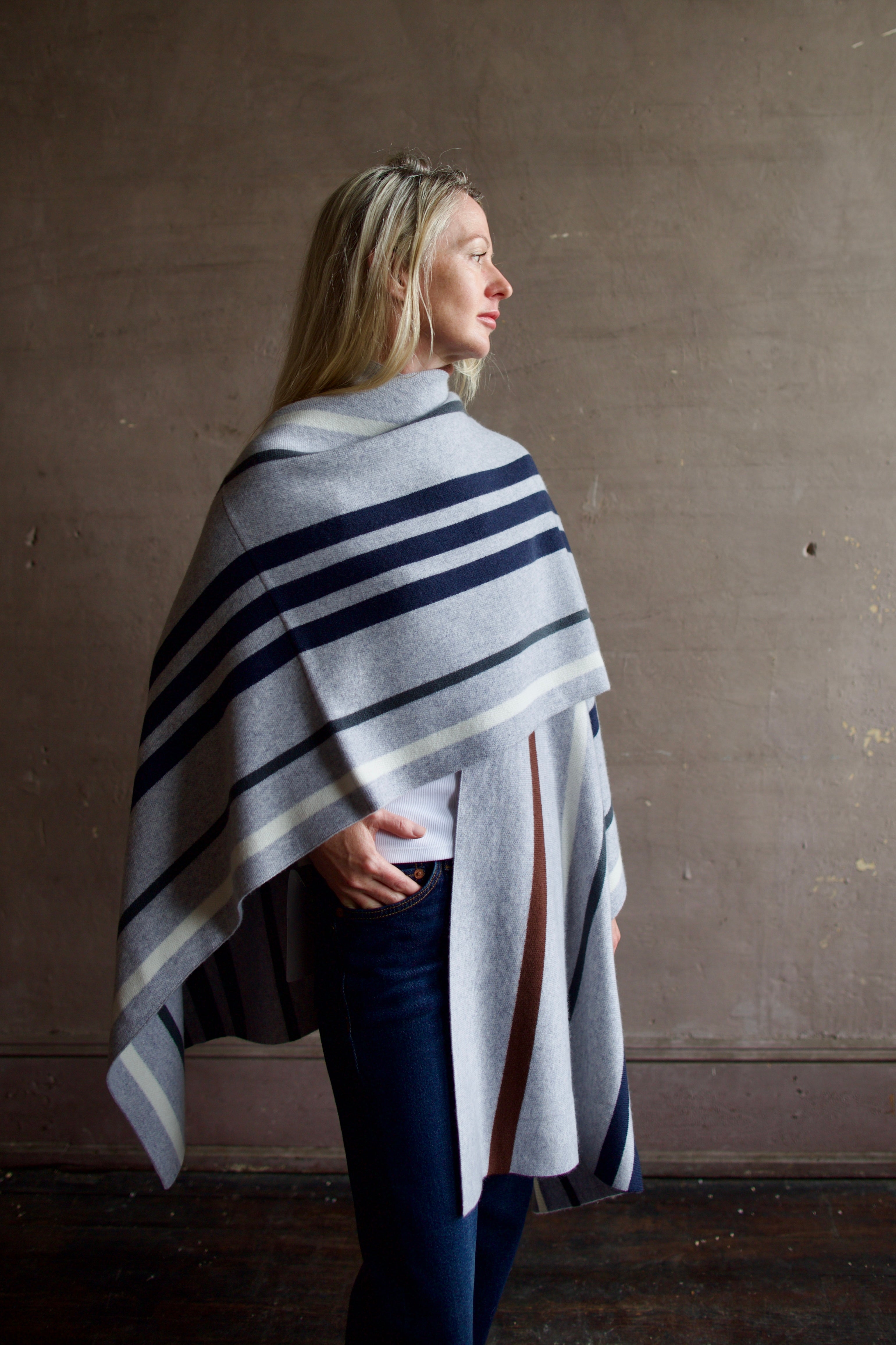 Mature Model wearing gray TWP luxury Italian cashmere poncho with brown and navy stripes