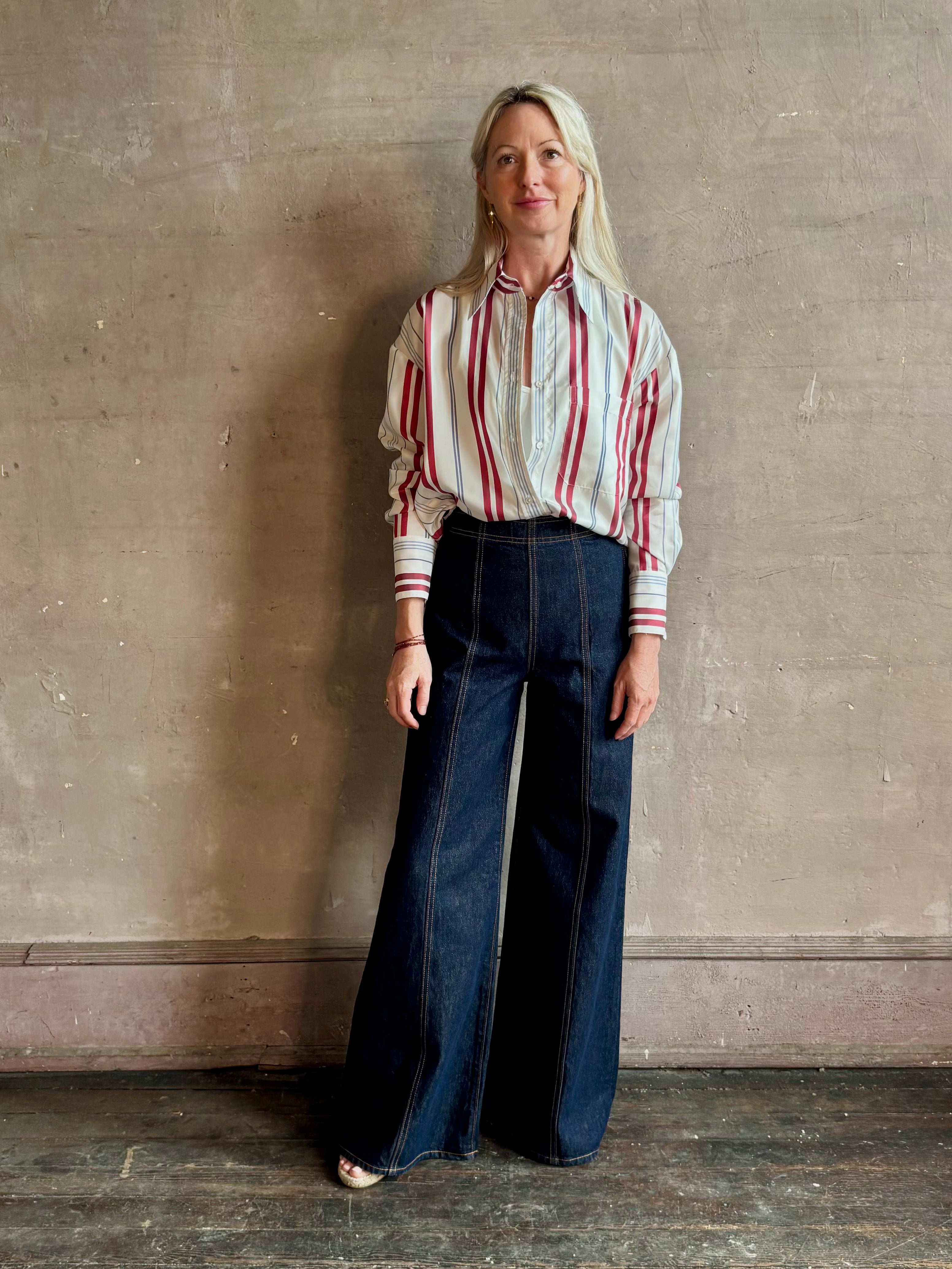 Mature woman wearing Big Joe Shirt from TWP rendered in an ivory, blue, and wine striped colorway and crafted from silk in the USA with collar, button front and wide cuffed long sleeves in a generous oversized fit