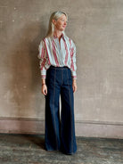 Mature woman wearing Big Joe Shirt from TWP rendered in an ivory, blue, and wine striped colorway and crafted from silk in the USA with collar, button front and wide cuffed long sleeves in a generous oversized fit