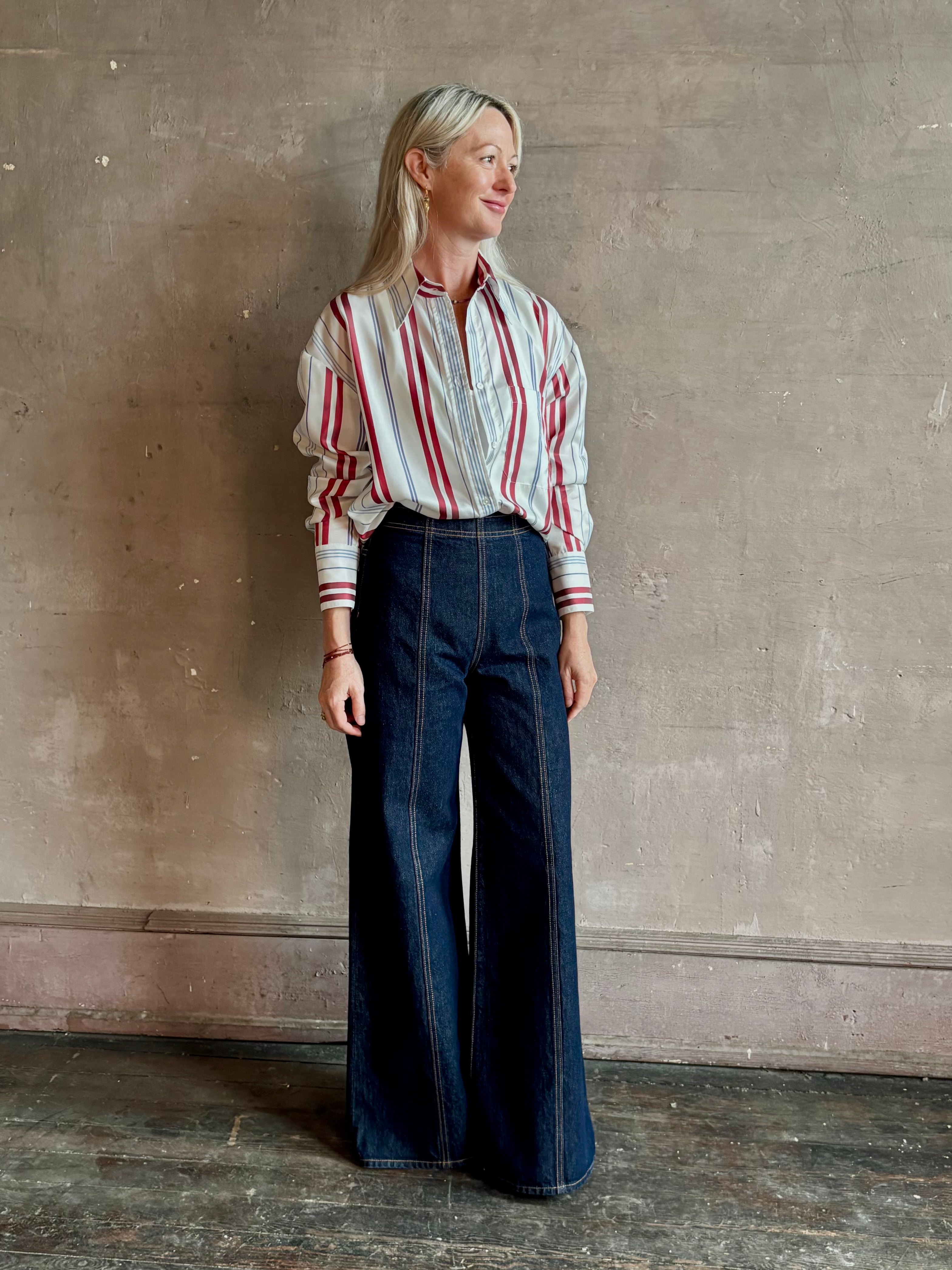 Mature woman wearing Big Joe Shirt from TWP rendered in an ivory, blue, and wine striped colorway and crafted from silk in the USA with collar, button front and wide cuffed long sleeves in a generous oversized fit