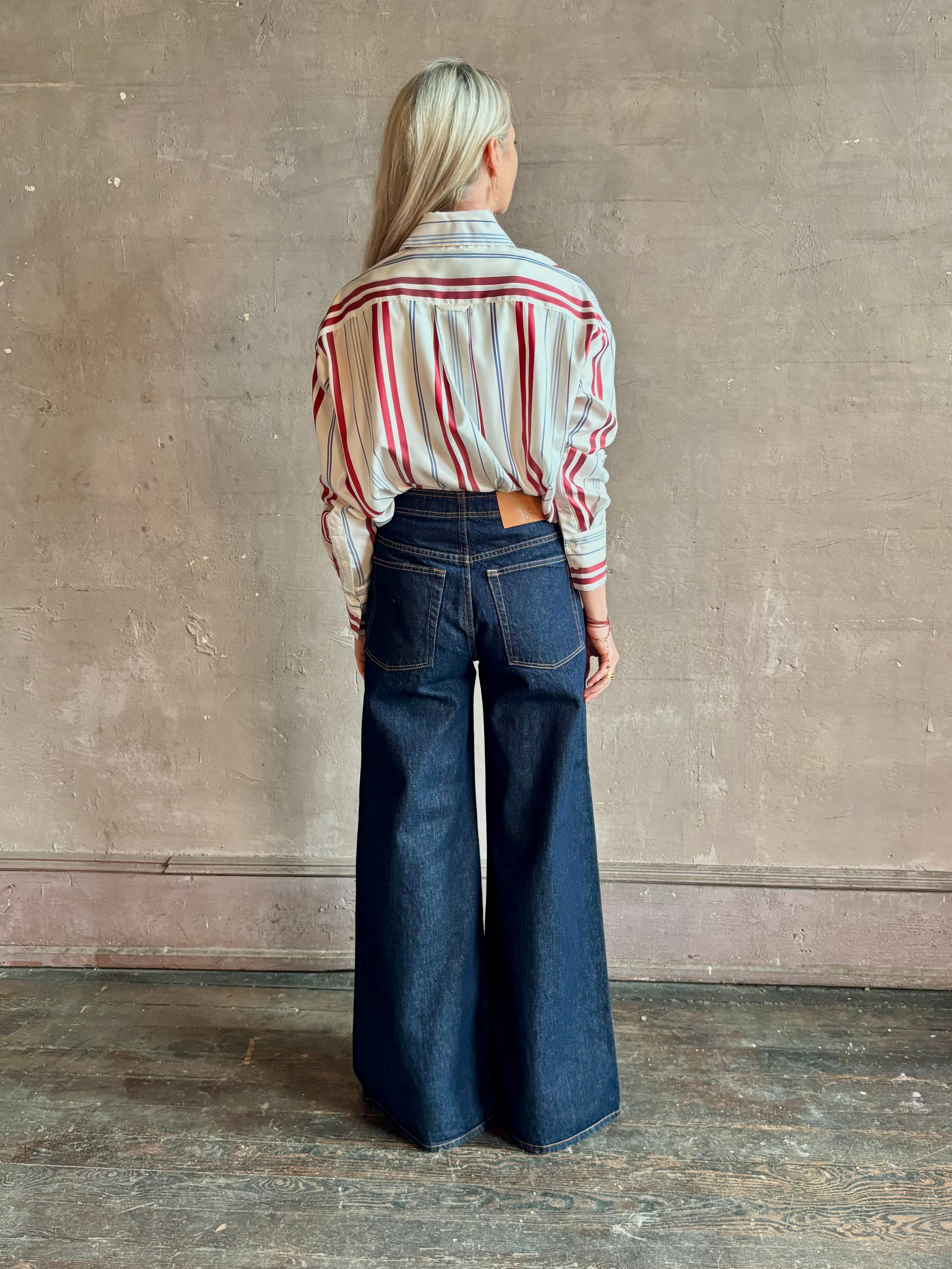 Mature woman wearing Big Joe Shirt from TWP rendered in an ivory, blue, and wine striped colorway and crafted from silk in the USA with collar, button front and wide cuffed long sleeves in a generous oversized fit
