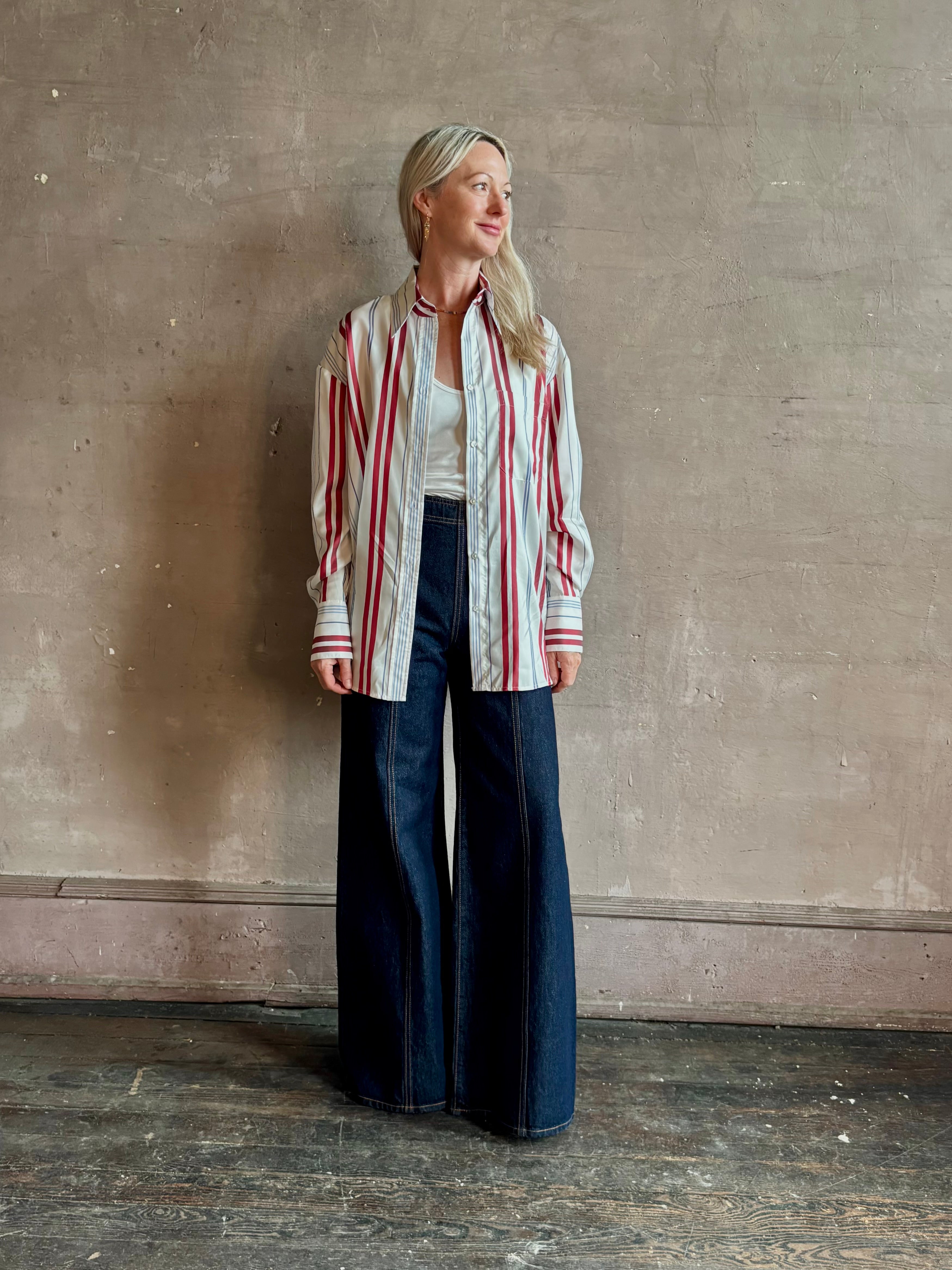Mature woman wearing Big Joe Shirt from TWP rendered in an ivory, blue, and wine striped colorway and crafted from silk in the USA with collar, button front and wide cuffed long sleeves in a generous oversized fit