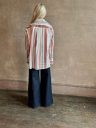 Mature woman wearing Big Joe Shirt from TWP rendered in an ivory, blue, and wine striped colorway and crafted from silk in the USA with collar, button front and wide cuffed long sleeves in a generous oversized fit