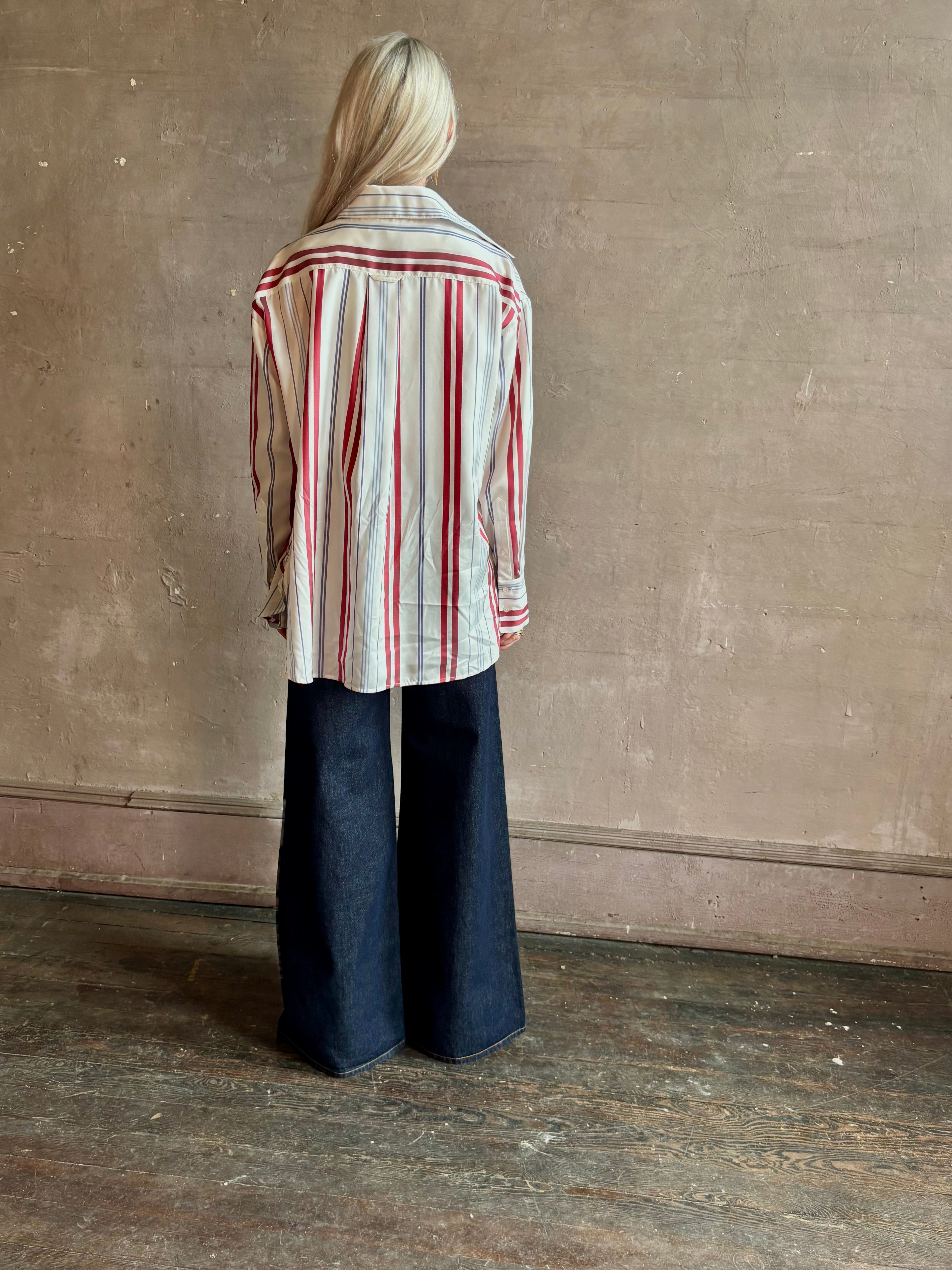 Mature woman wearing Big Joe Shirt from TWP rendered in an ivory, blue, and wine striped colorway and crafted from silk in the USA with collar, button front and wide cuffed long sleeves in a generous oversized fit