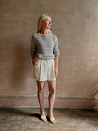 Mature woman wearing elevated tailored Cisco Shorts from TWP rendered in a soft bone white and crafted in the USA using a viscose and  linen blend fabric with side seam pockets, belt loops, single front pleat and cuffed at the bottom