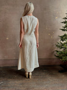 Mature woman wearing elegant Crew Neck maxi A-Line Dress with Darts from TWP rendered in a soft off white and crafted in the USA from a viscose and linen fabric blend with side seam pockets and sleeveless