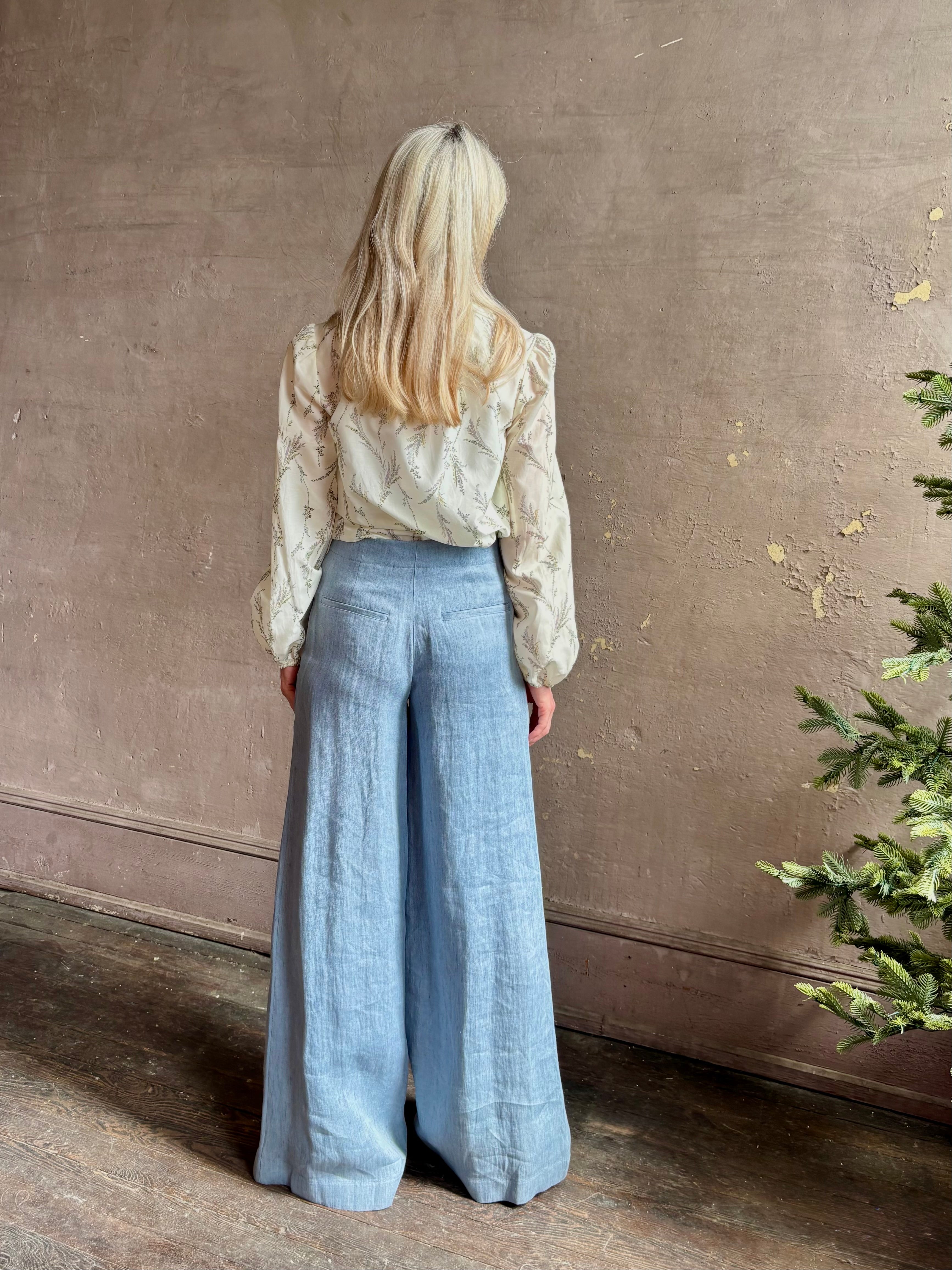 Mature woman wearing luxury brand TWP Demie High Rise wide leg indigo hemp Pants offers timeless  refinement and expert craftsmanship