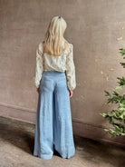 Mature woman wearing luxury brand TWP Demie High Rise wide leg indigo hemp Pants offers timeless  refinement and expert craftsmanship
