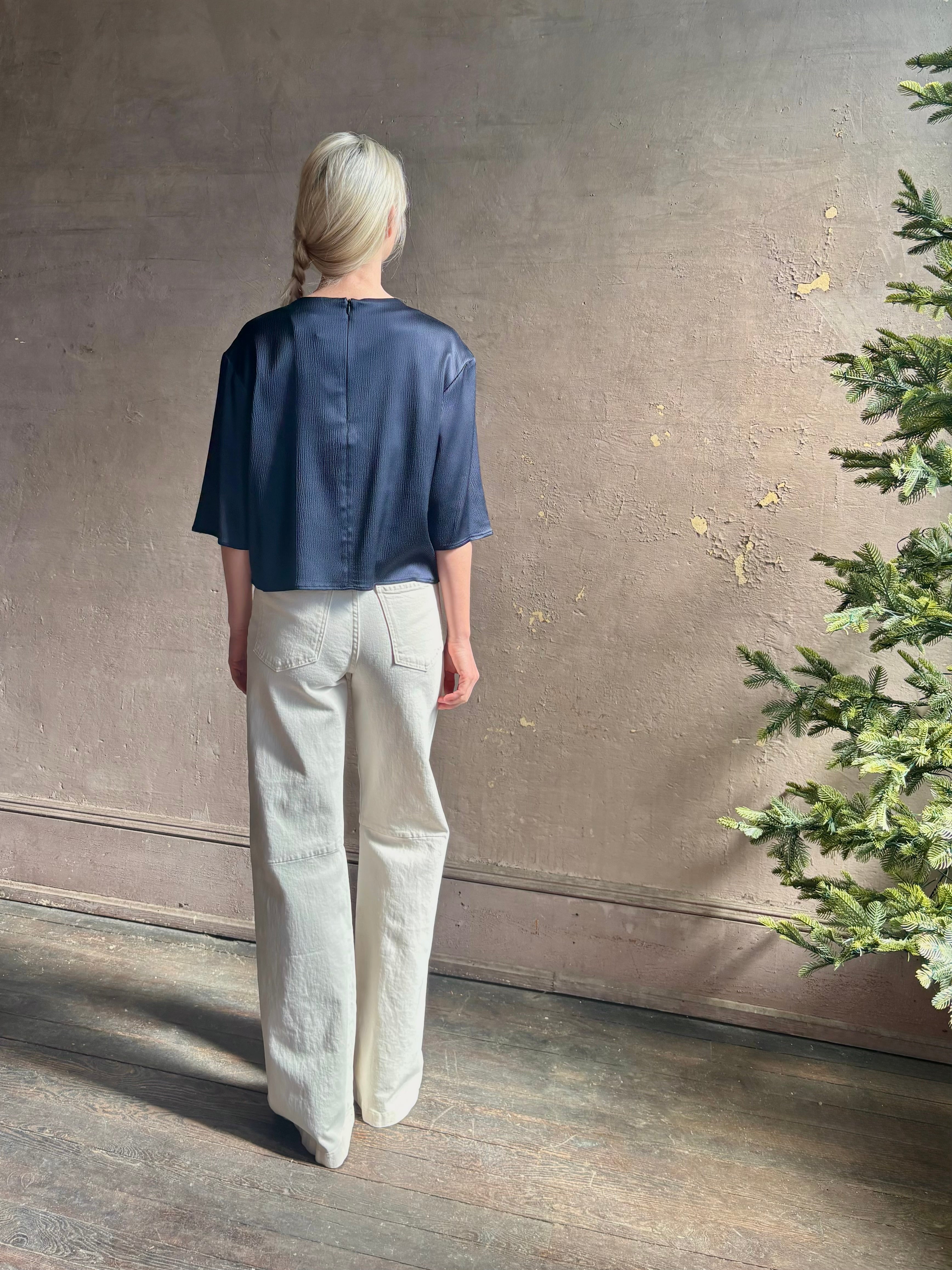 Mature woman wearing Women's luxury  clothing brand TWP Ex T in premium hammered satin with short sleeves crew neck and a casual front pocket rendered in a beautiful navy blue hue