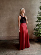 Mature woman wearing Flowy Maxi A-Line Skirt from TWP rendered in a rich red currant and crafted from a luxurious  silk blend with hidden seam zip closure and tailored waistband