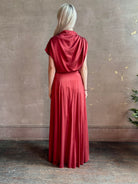 Mature woman wearing Flowy Maxi A-Line Skirt from TWP rendered in a rich red currant and crafted from a luxurious  silk blend with hidden seam zip closure and tailored waistband