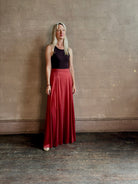 Mature woman wearing Flowy Maxi A-Line Skirt from TWP rendered in a rich red currant and crafted from a luxurious  silk blend with hidden seam zip closure and tailored waistband