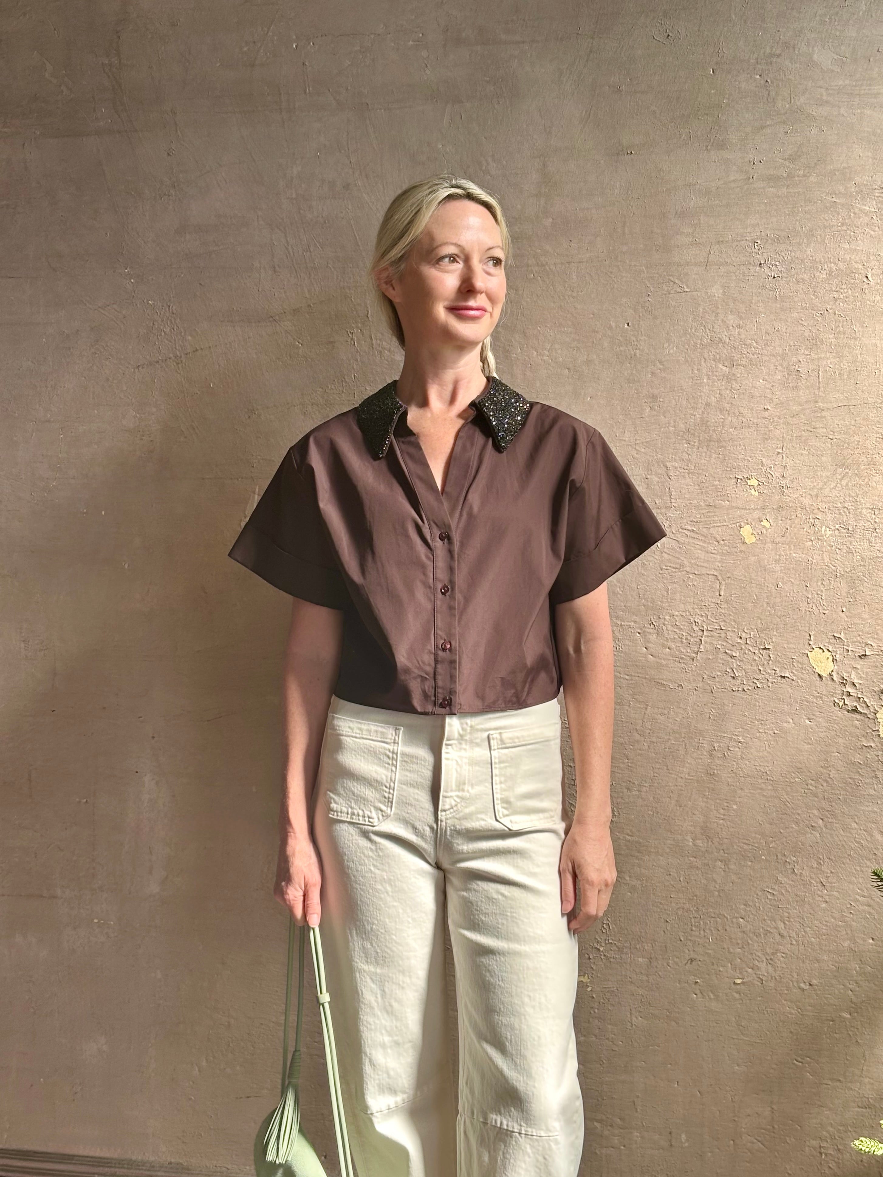 Mature woman wearing Forever and Always with Crystal Collar Top from TWP women's luxury designer blouse rendered in chocolate brown and crafted from 100% cotton in the USA with crystal collar, short sleeves and reversible