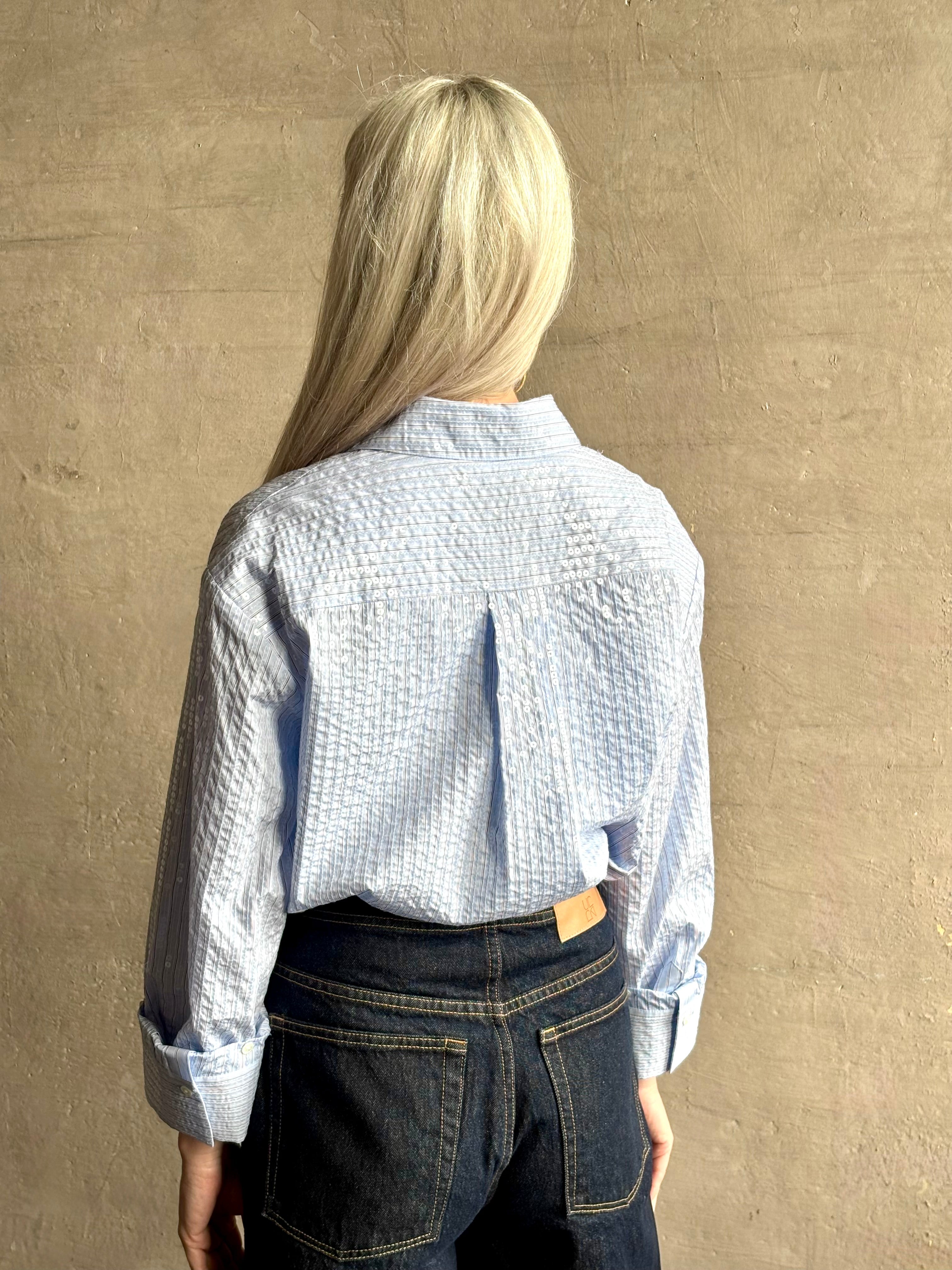 Mature woman wearing JD blue and white stripe collared button-down shirt by TWP with sequin embellishments