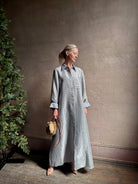 Mature woman wearing luxury Jenny's Gown from designer TWP rendered in a lumines white and blue stripe print and crafted in USA from a viscose and lorex blend this lightweight long sleeve maxi  dress drapes beautifully with a flowing quality that moves with understated grace 