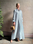 Mature woman wearing luxury Jenny's Gown from designer TWP rendered in a lumines white and blue stripe print and crafted in USA from a viscose and lorex blend this lightweight long sleeve maxi  dress drapes beautifully with a flowing quality that moves with understated grace 