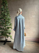 Mature woman wearing luxury Jenny's Gown from designer TWP rendered in a lumines white and blue stripe print and crafted in USA from a viscose and lorex blend this lightweight long sleeve maxi  dress drapes beautifully with a flowing quality that moves with understated grace 