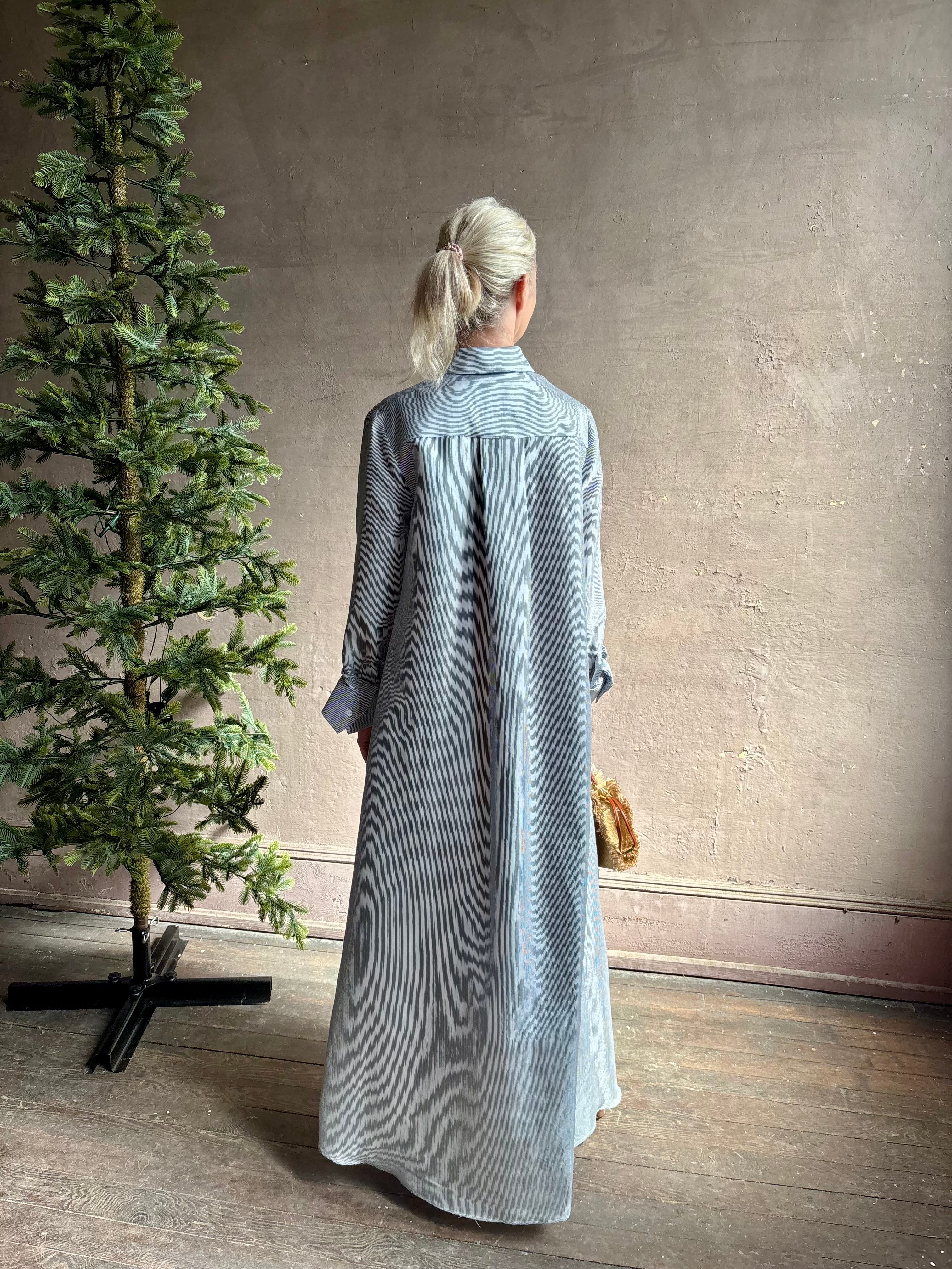 Mature woman wearing luxury Jenny's Gown from designer TWP rendered in a lumines white and blue stripe print and crafted in USA from a viscose and lorex blend this lightweight long sleeve maxi  dress drapes beautifully with a flowing quality that moves with understated grace 