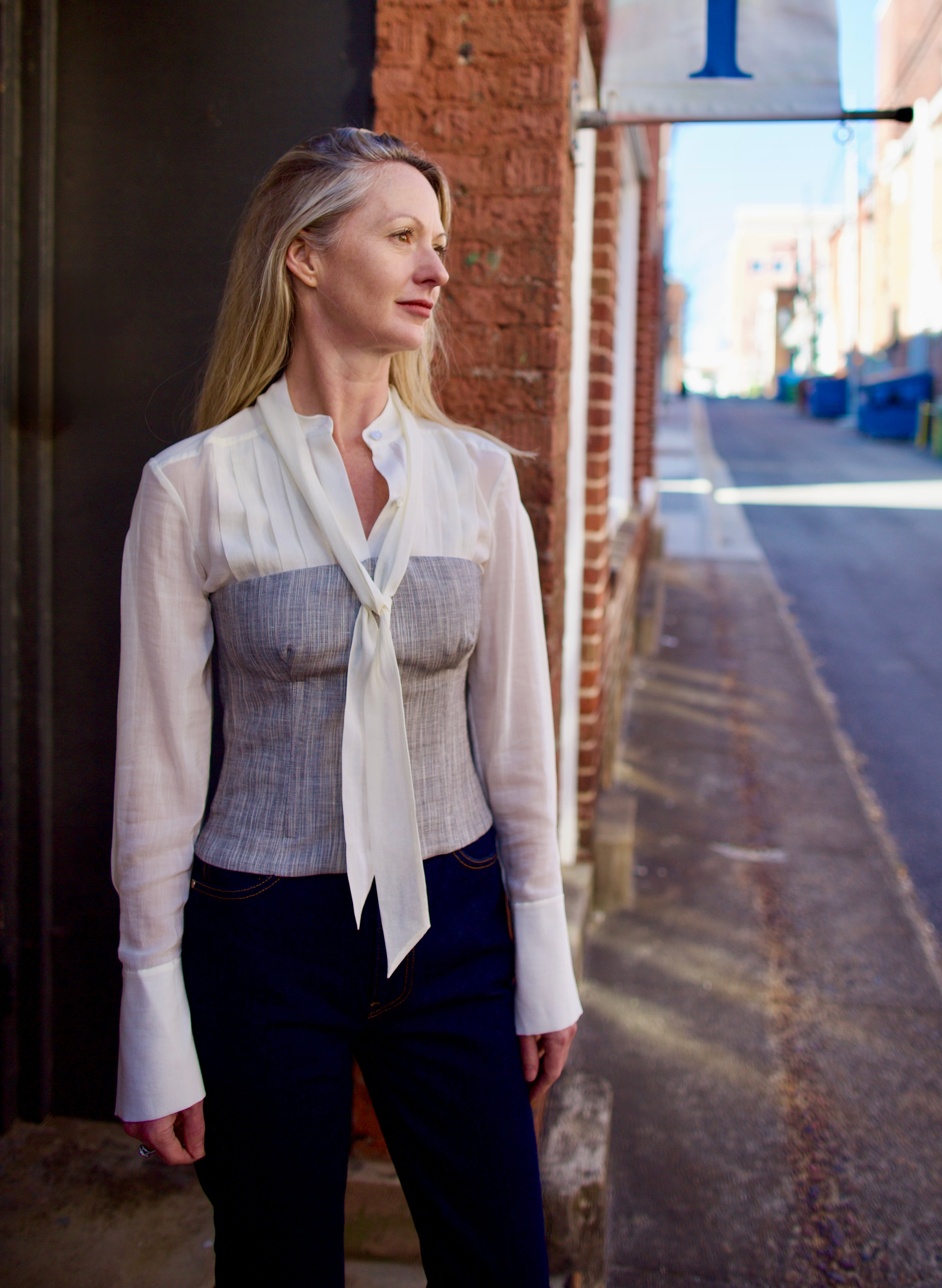 Mature woman wearing luxury brand TWP Jillian cotton-wool bustier in heather grey with bust darts zip closure layered over blouse
