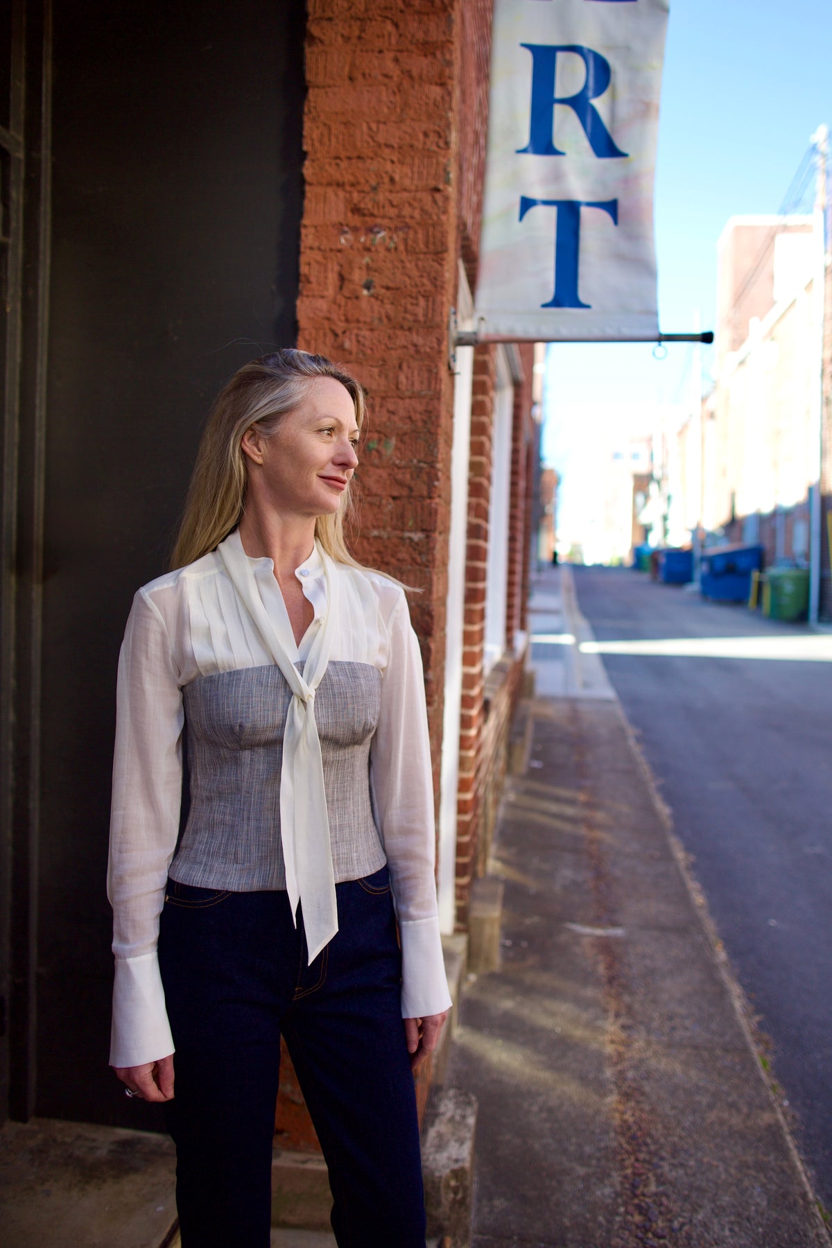 Mature woman wearing luxury brand TWP Jillian cotton-wool bustier in heather grey with bust darts zip closure over long sleeve blouse