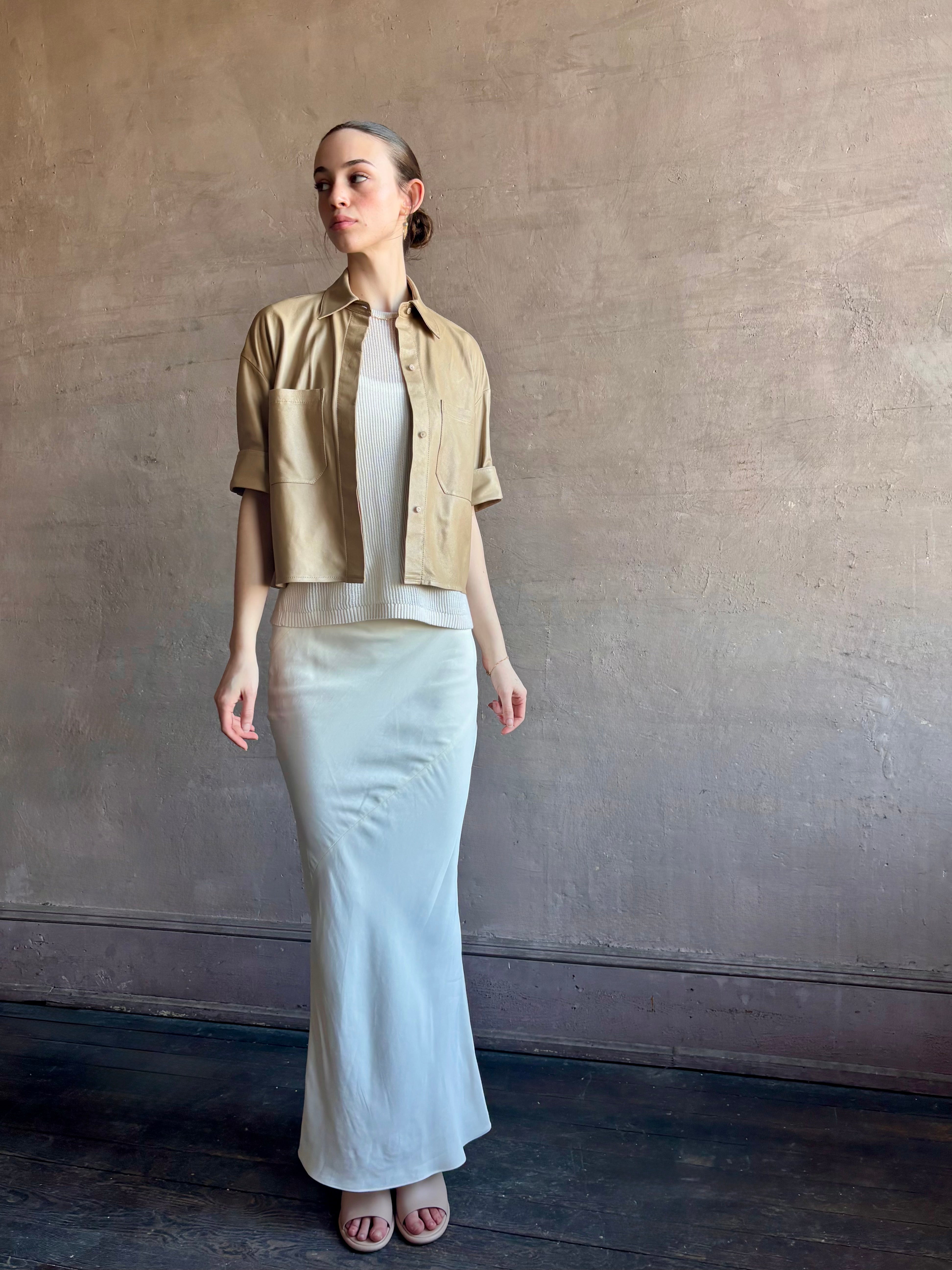 Woman wearing luxury designer TWP premium Lambskin Leather button up collared shirt with cuffed short sleeves in a neutral khaki that can double as a lightweight jacket