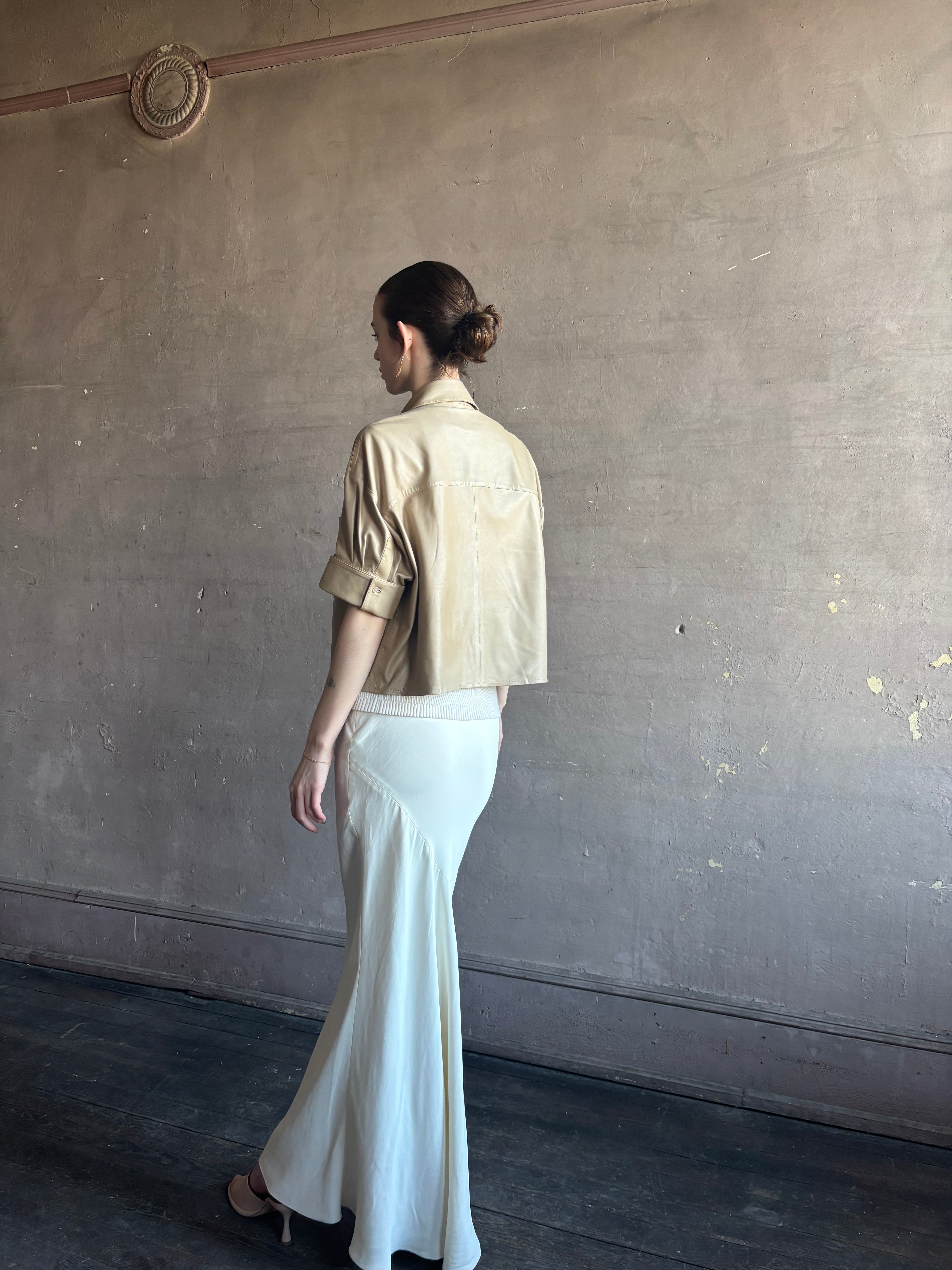 Woman wearing luxury designer TWP premium Lambskin Leather button up collared shirt with cuffed short sleeves in a neutral khaki that can double as a lightweight jacket