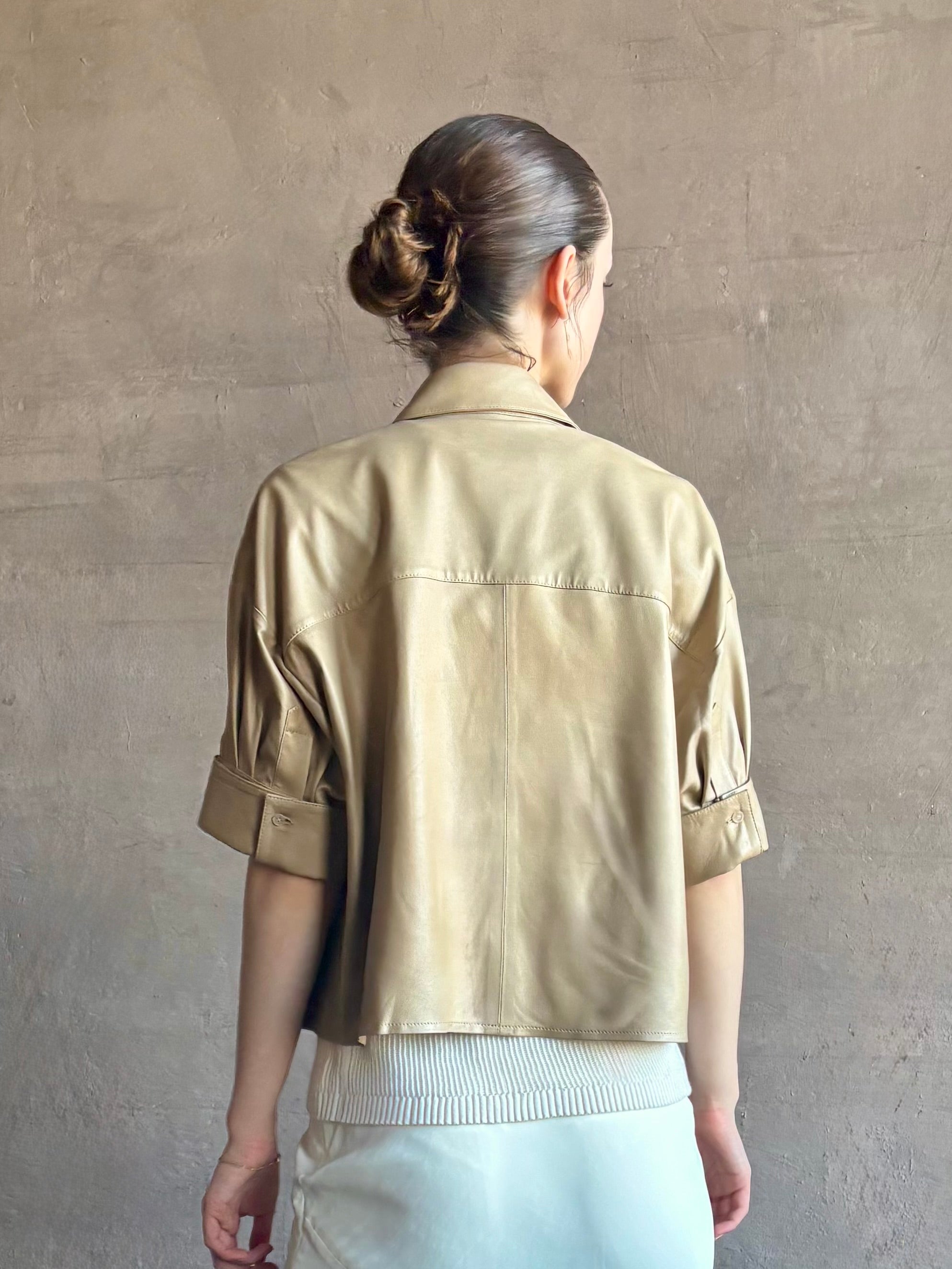 Woman wearing luxury designer TWP premium Lambskin Leather button up collared shirt with cuffed short sleeves in a neutral khaki that can double as a lightweight jacket