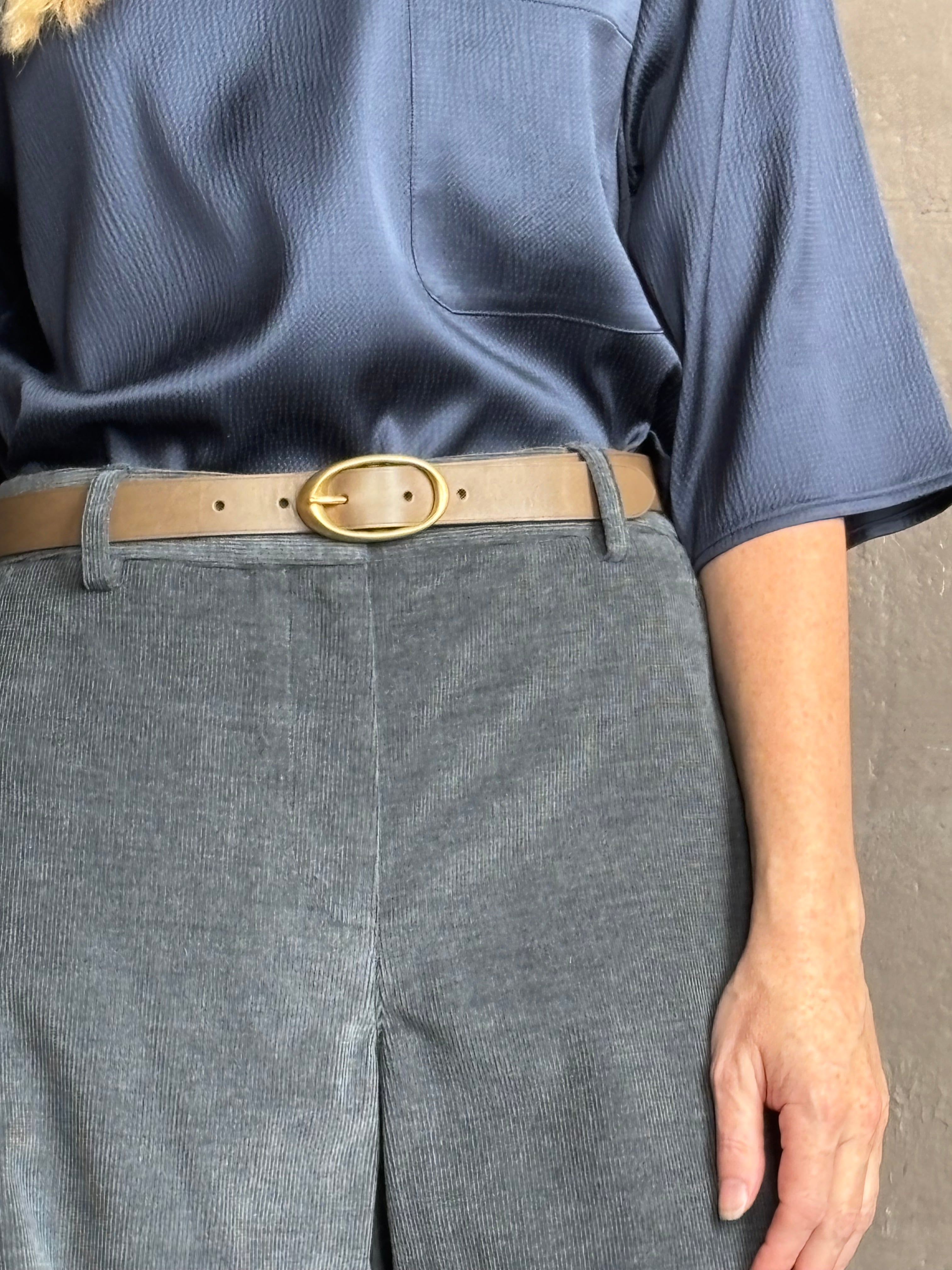 Close up image of woman wearing TWP narrow belt in mink light brown colorway and fabricated with premium leather and brass oval buckle