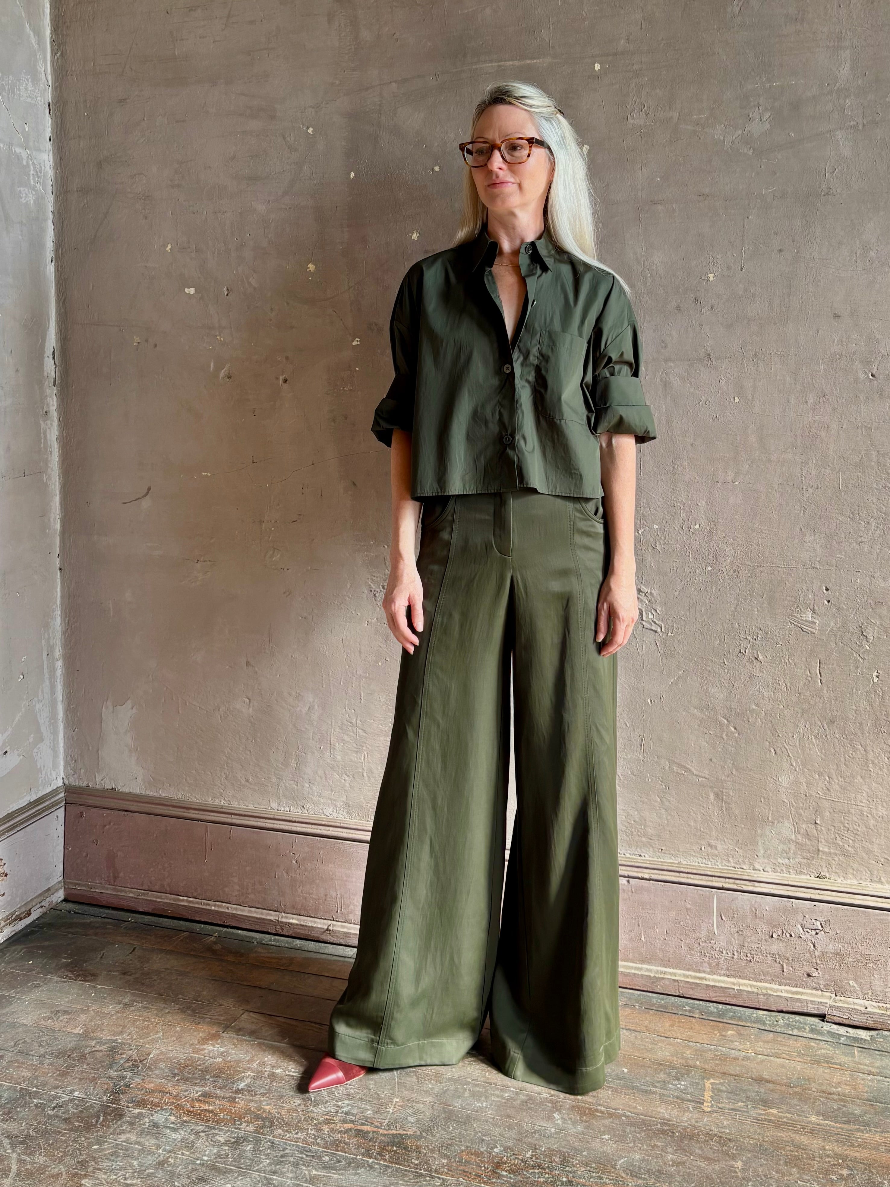 Mature woman wearing TWP next ex cotton poplin dark green rosin button-up shirt with rolled sleeves and collar