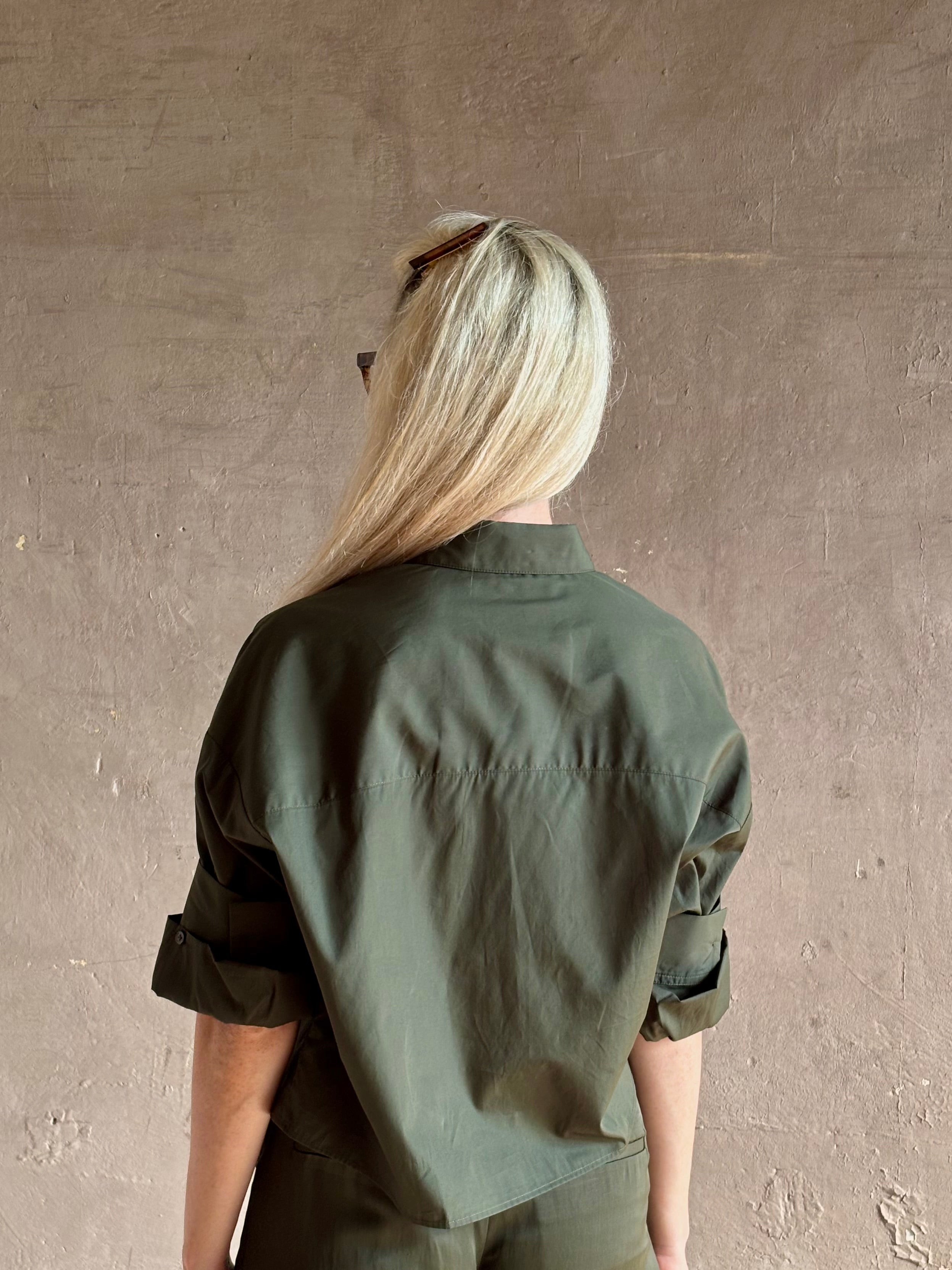 Mature woman wearing TWP next ex cotton poplin dark green rosin button-up shirt with rolled sleeves and collar