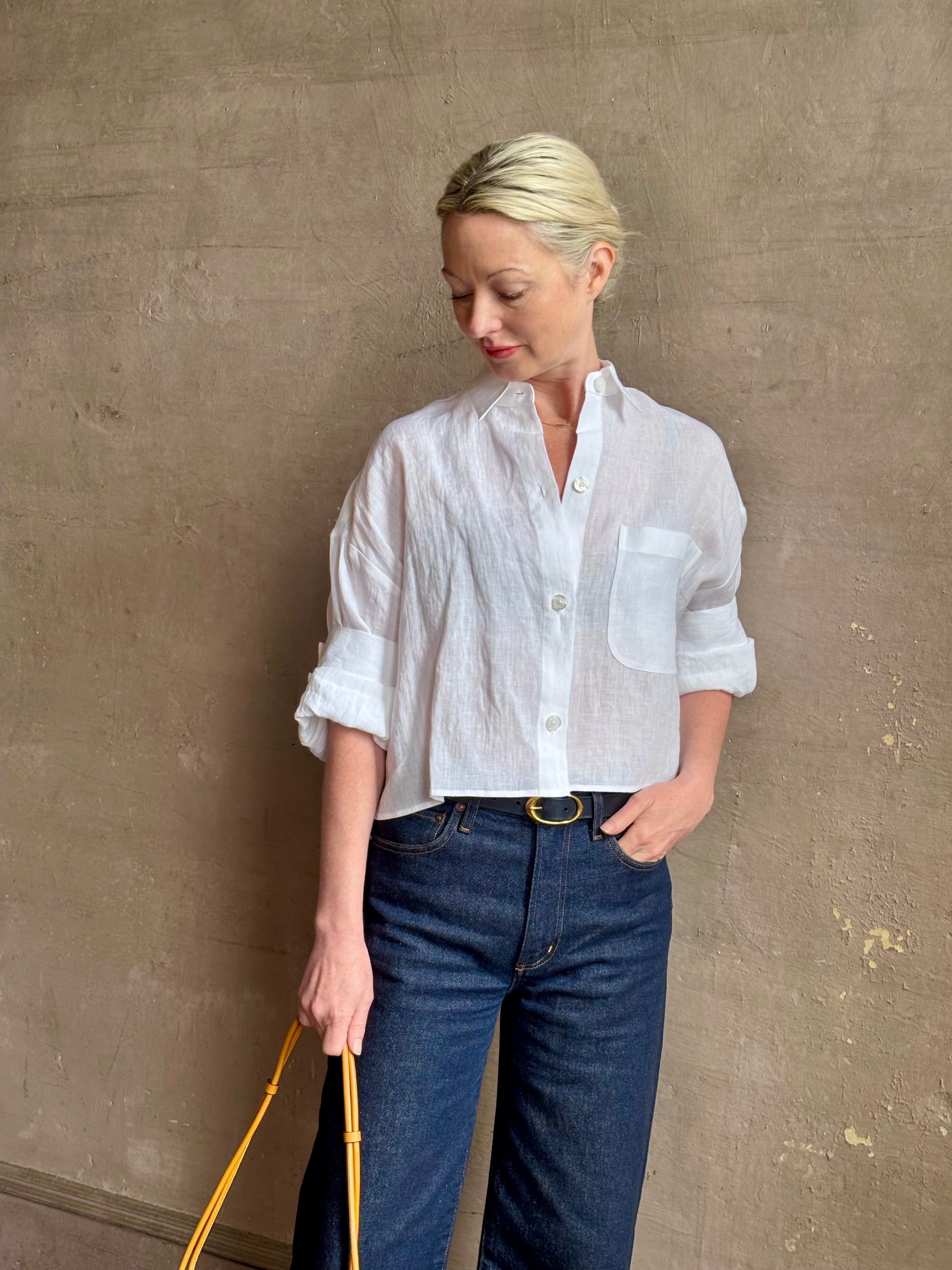 Mature woman wearing the Next Ex Top from TWP rendered in a crisp white and crafted from premium linen in New York City, this luxury linen top offers effortless cool girl with an intentionally oversized boxy silhouette with tailored half sleeve cuffs, collared button - down menswear inspired with a single front pocket