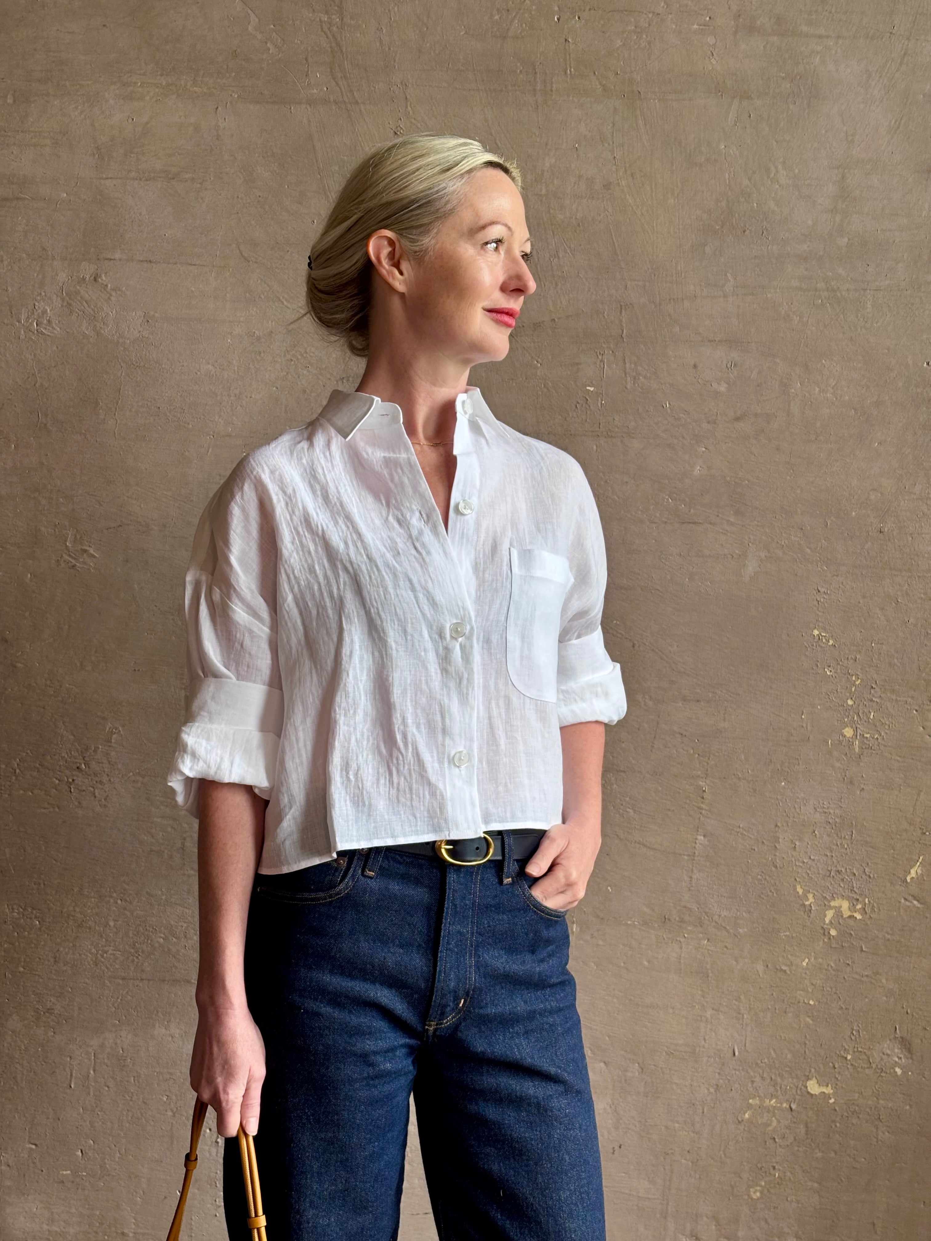 Mature woman wearing the Next Ex Top from TWP rendered in a crisp white and crafted from premium linen in New York City, this luxury linen top offers effortless cool girl with an intentionally oversized boxy silhouette with tailored half sleeve cuffs, collared button - down menswear inspired with a single front pocket