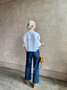Mature woman wearing the Next Ex Top from TWP rendered in a crisp white and crafted from premium linen in New York City, this luxury linen top offers effortless cool girl with an intentionally oversized boxy silhouette with tailored half sleeve cuffs, collared button - down menswear inspired with a single front pocket
