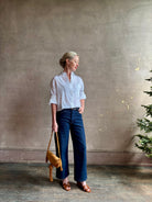 Mature woman wearing the Next Ex Top from TWP rendered in a crisp white and crafted from premium linen in New York City, this luxury linen top offers effortless cool girl with an intentionally oversized boxy silhouette with tailored half sleeve cuffs, collared button - down menswear inspired with a single front pocket