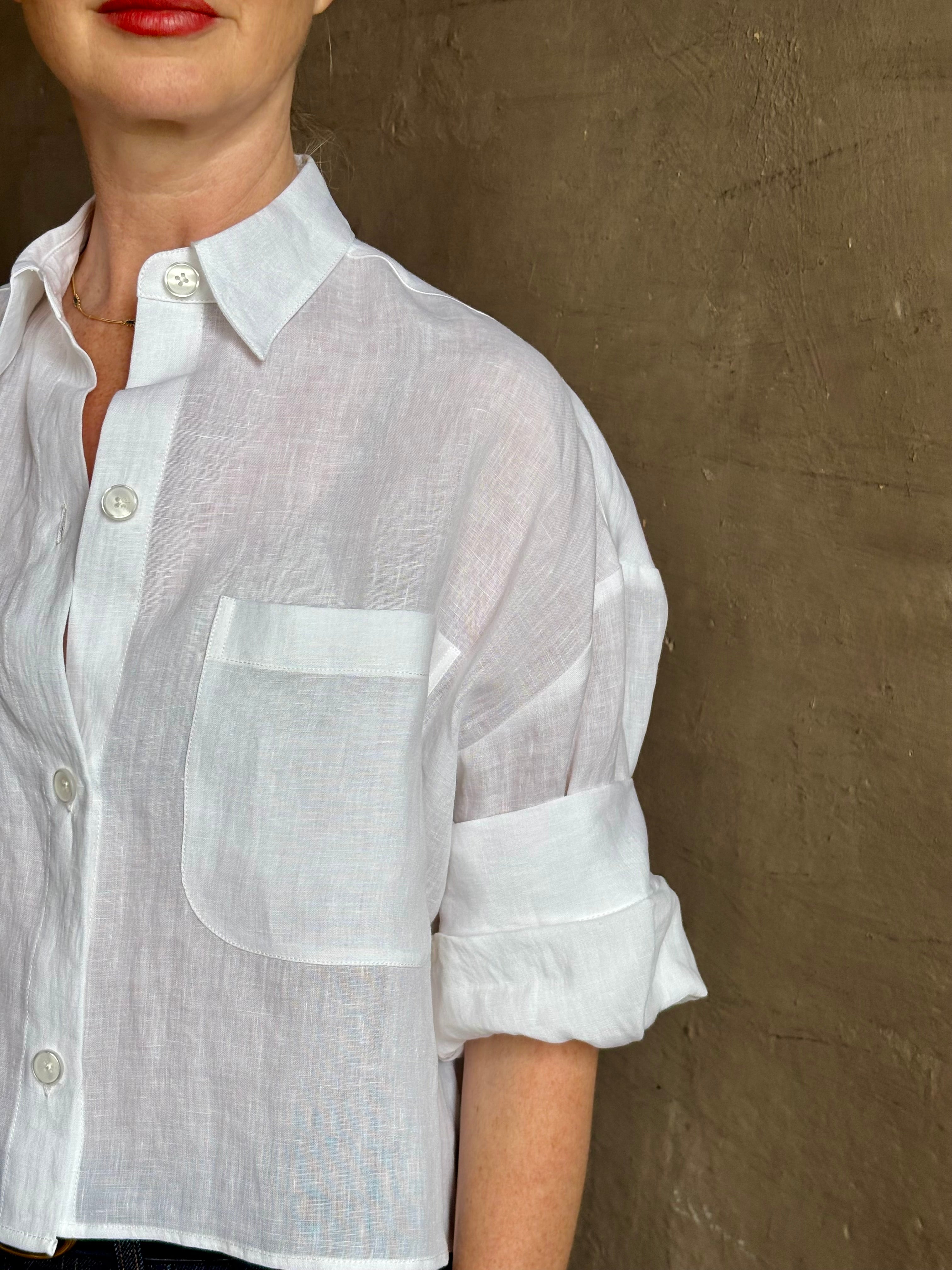 Mature woman wearing the Next Ex Top from TWP rendered in a crisp white and crafted from premium linen in New York City, this luxury linen top offers effortless cool girl with an intentionally oversized boxy silhouette with tailored half sleeve cuffs, collared button - down menswear inspired with a single front pocket