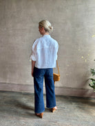 Mature woman wearing the Next Ex Top from TWP rendered in a crisp white and crafted from premium linen in New York City, this luxury linen top offers effortless cool girl with an intentionally oversized boxy silhouette with tailored half sleeve cuffs, collared button - down menswear inspired with a single front pocket