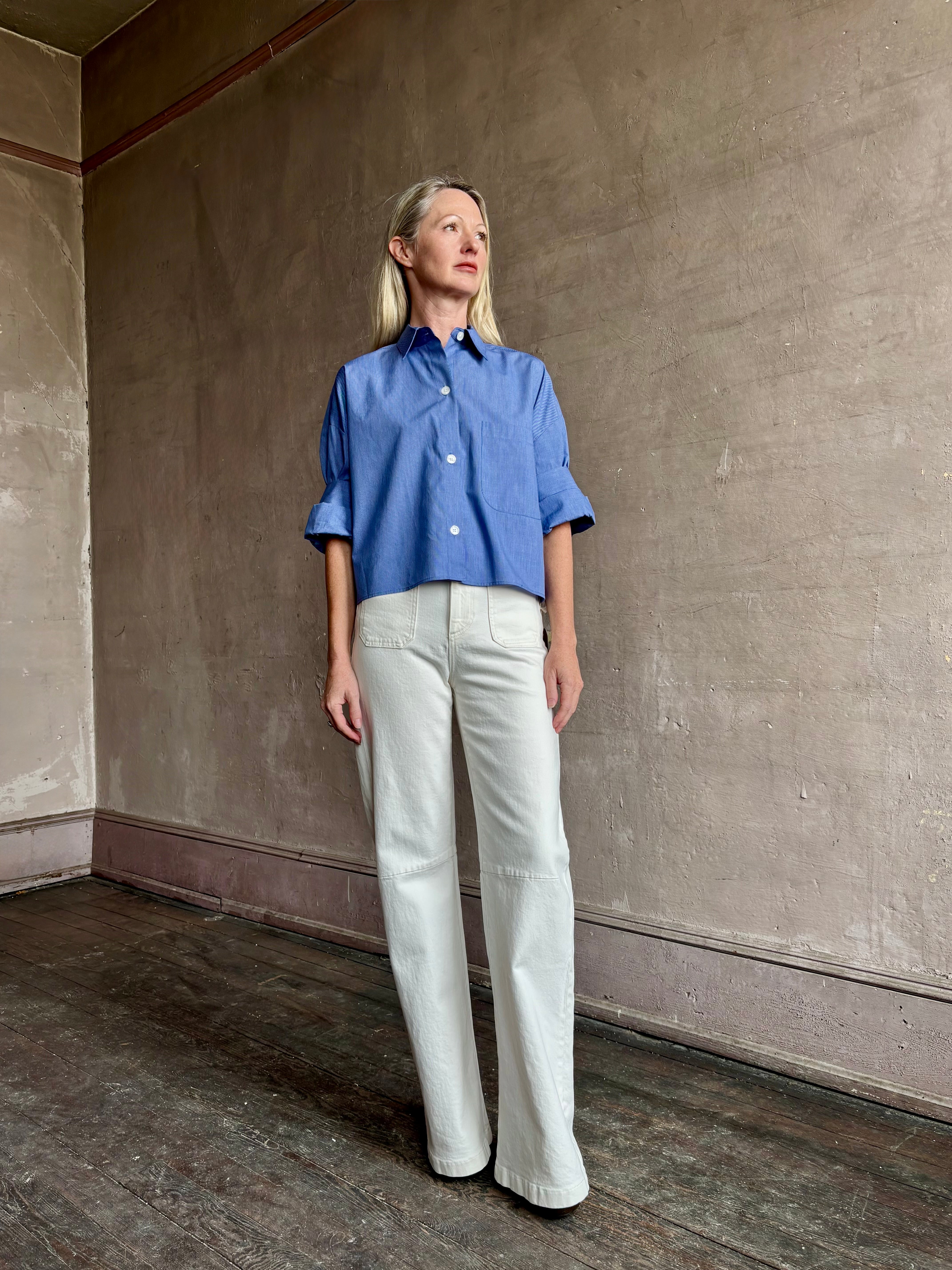 Image of mature model wearing classic cotton poplin button down next ex top by luxury brand TWP in a blue and white stripe.