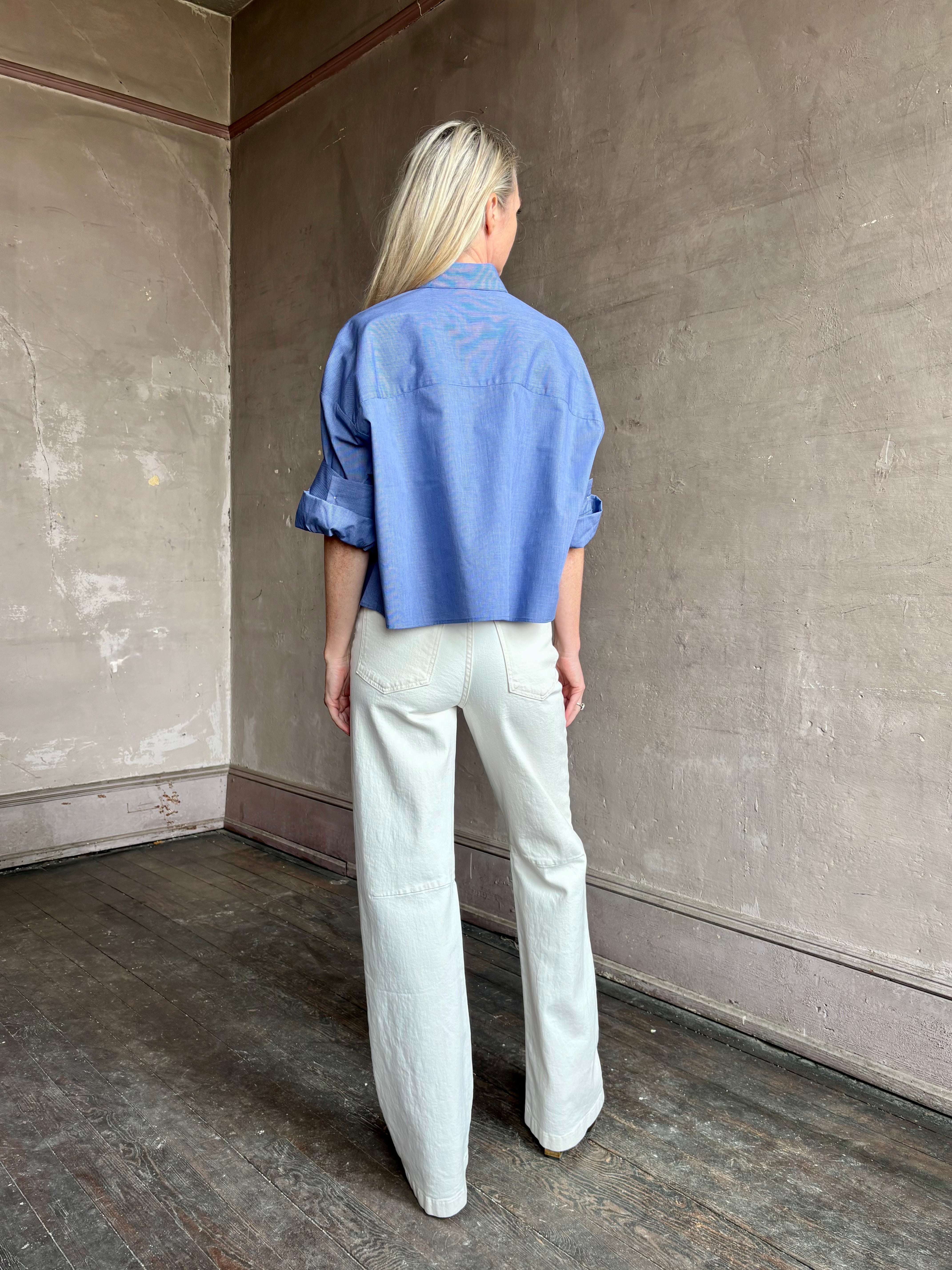 Image of mature model wearing classic cotton poplin button down next ex top by luxury brand TWP in a blue and white stripe.