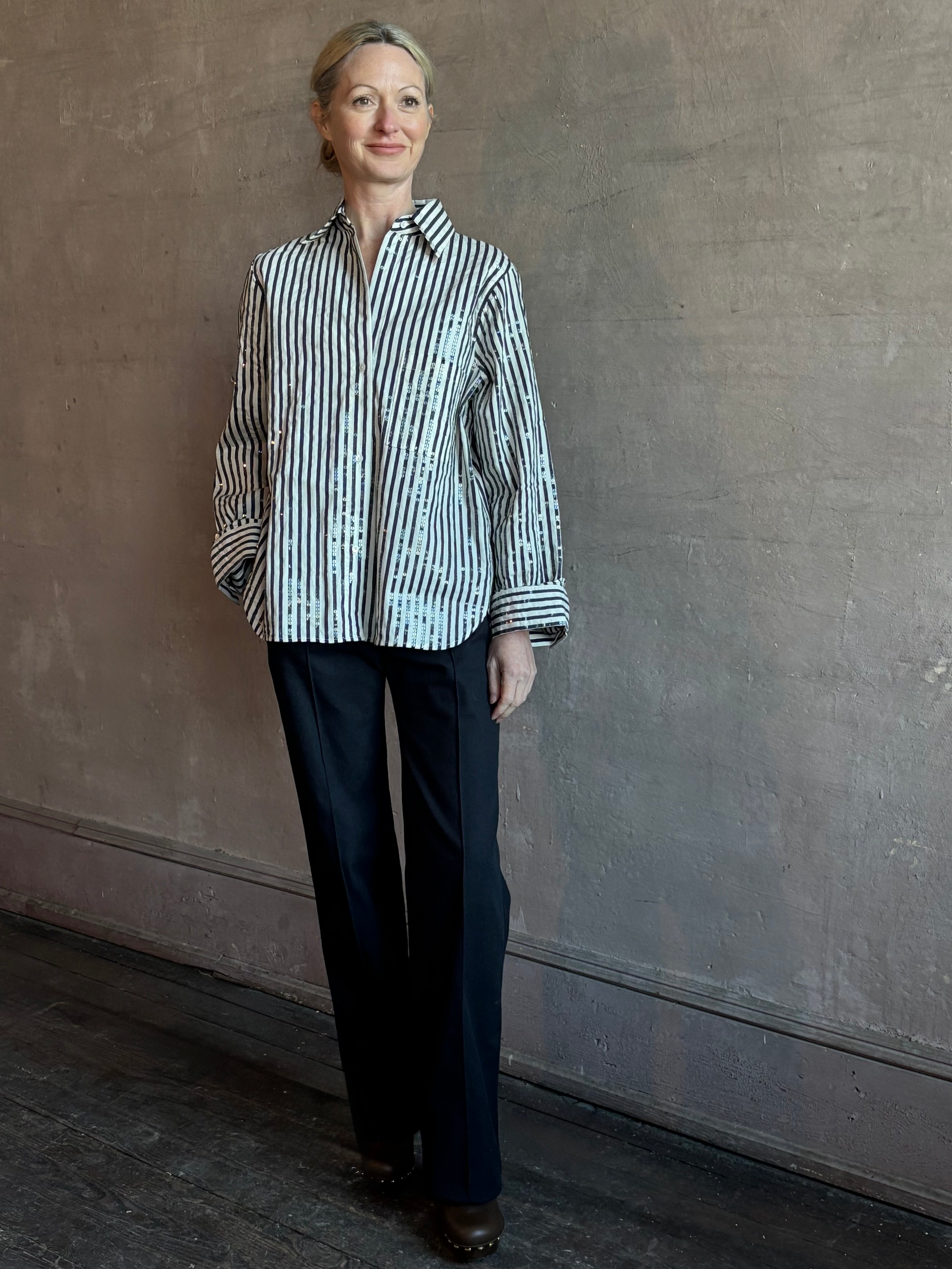 Mature woman wearing TWP premium cotton-blend button down indigo striped shirt with sequins, long sleeve and collar