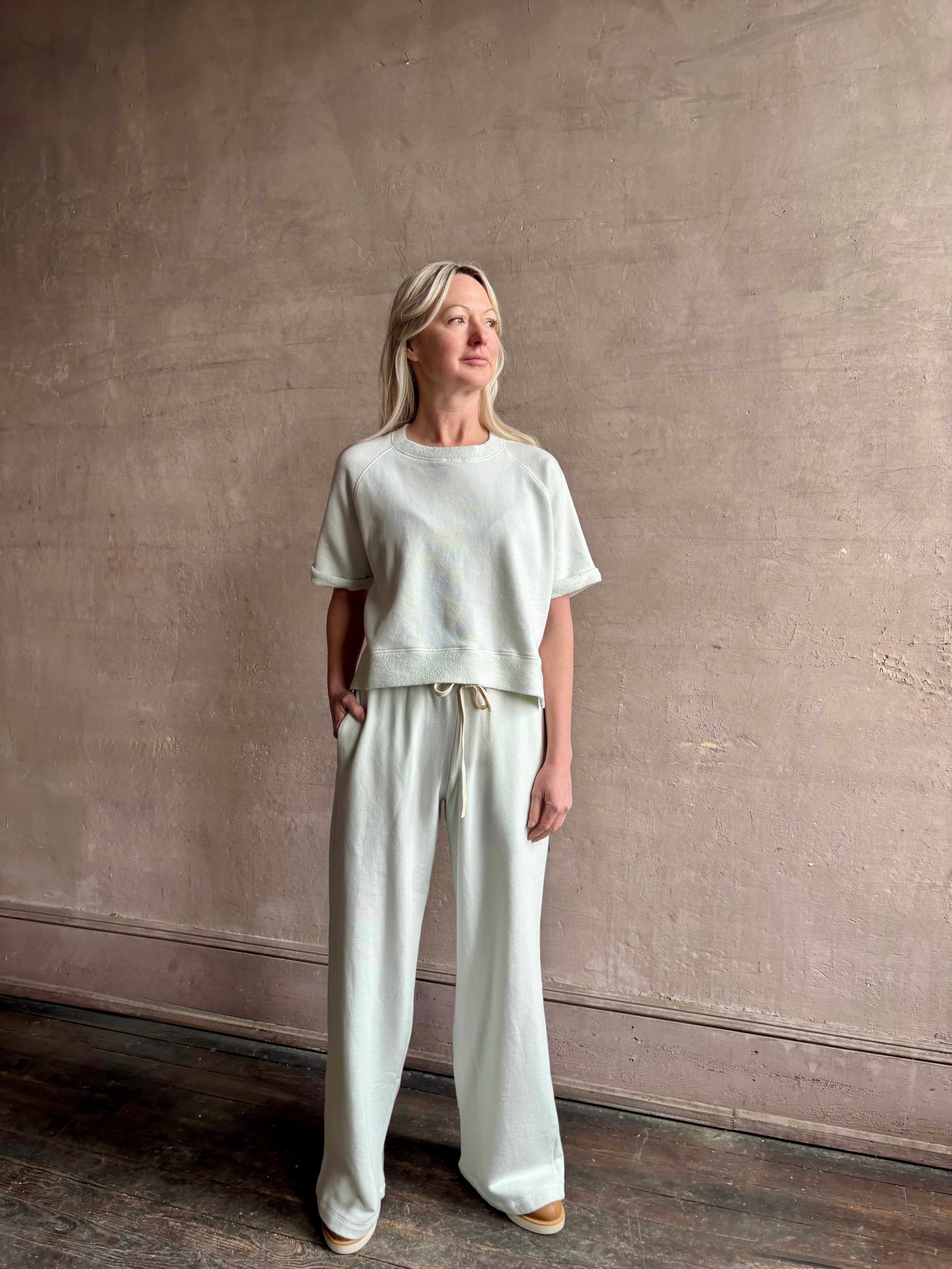 Mature woman wearing the PJ Pant from TWP is a luxuriously relaxed women's designer lounge pant crafted from cotton with a straight leg and effortless pull-on waist 