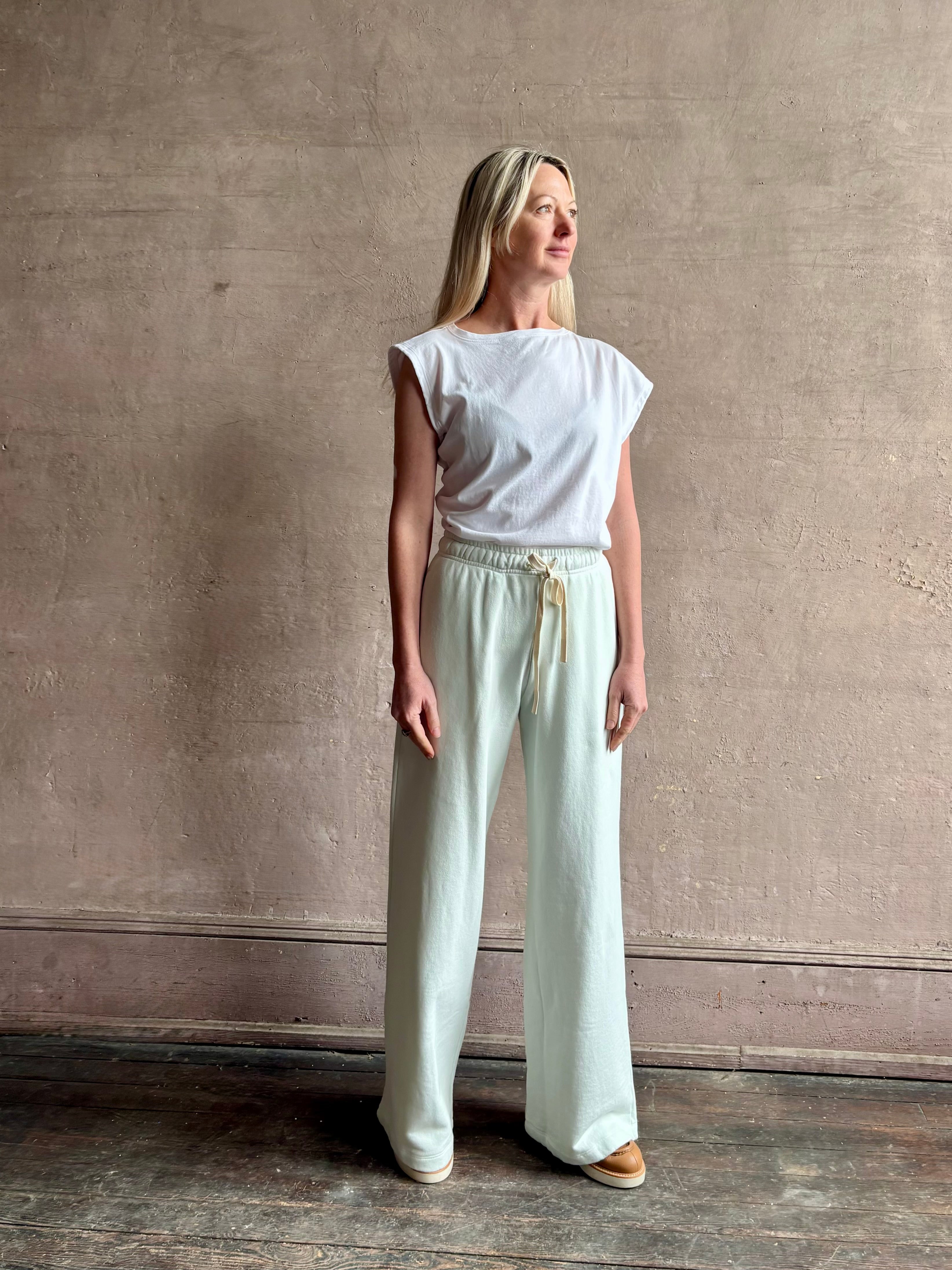 Mature woman wearing the PJ Pant from TWP is a luxuriously relaxed women's designer lounge pant crafted from cotton with a straight leg and effortless pull-on waist 