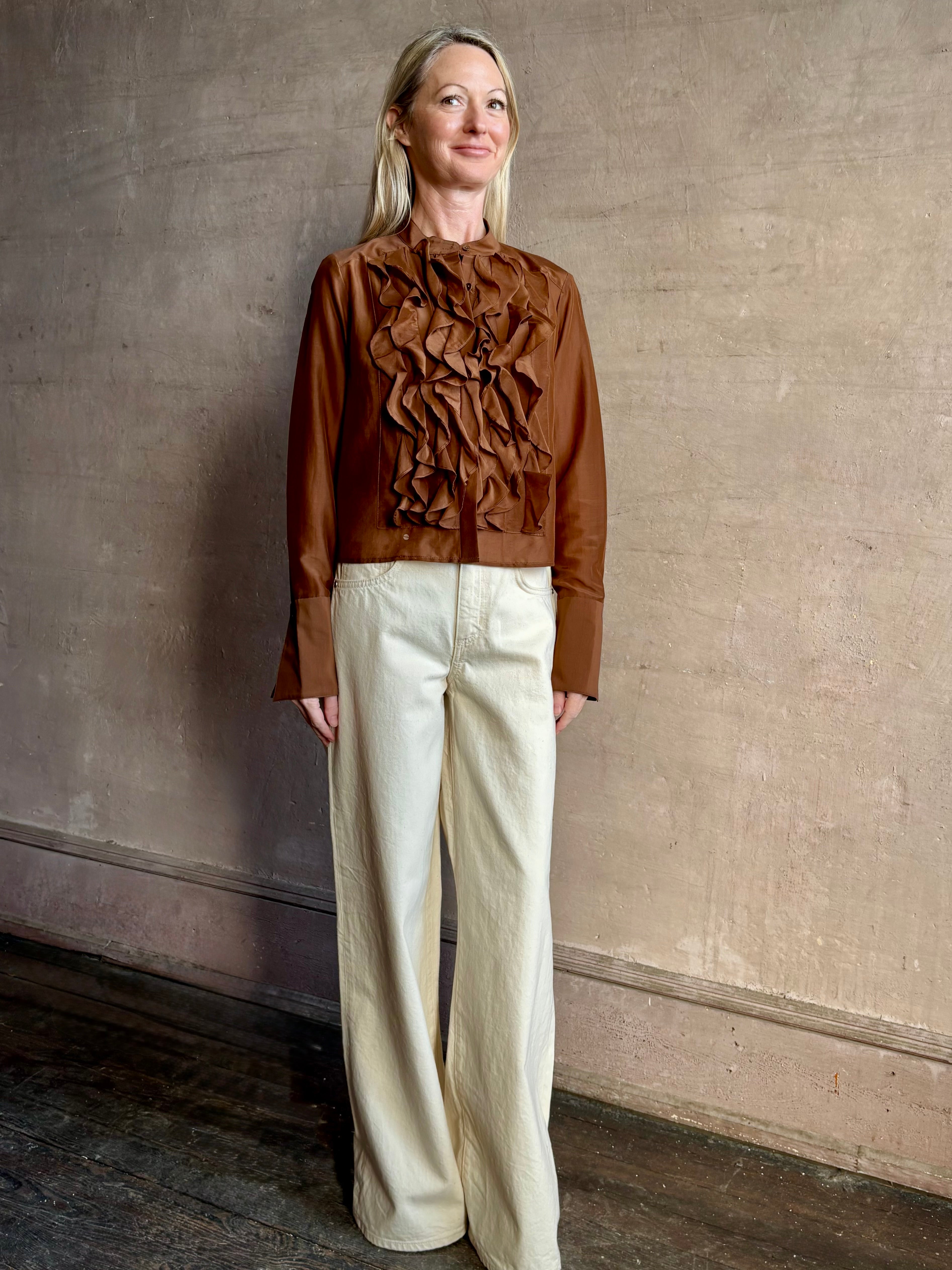 Image of woman wearing premium cotton silk TWP Patti Blouse in Emperador brown with ruffle front and long sleeves