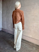 Image of woman wearing premium cotton silk TWP Patti Blouse in Emperador brown with ruffle front and long sleeves