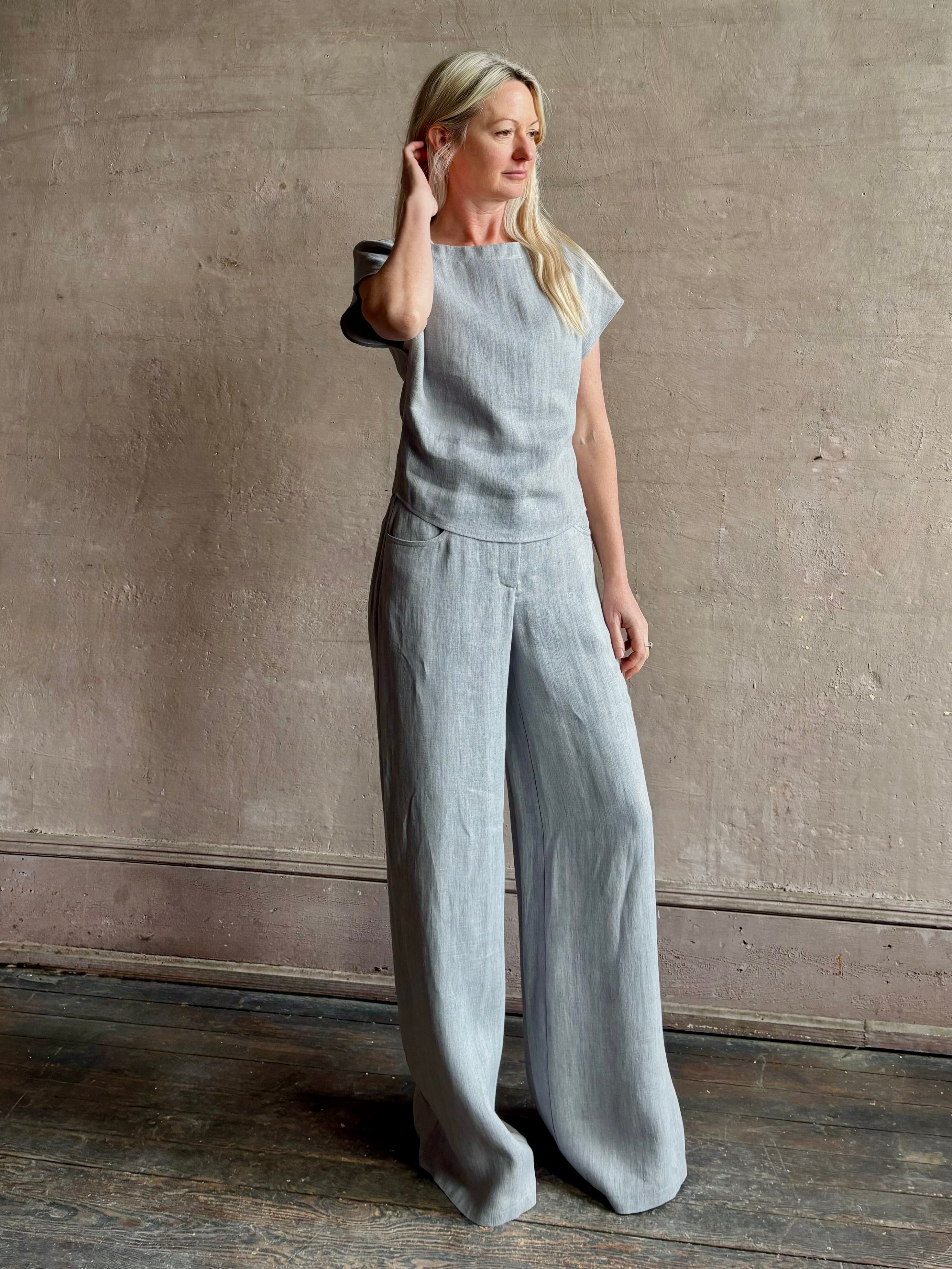 Mature woman wearing the Simple T Top from TWP that is rendered in a light heather grey hemp with short sleeves and boat neckline
